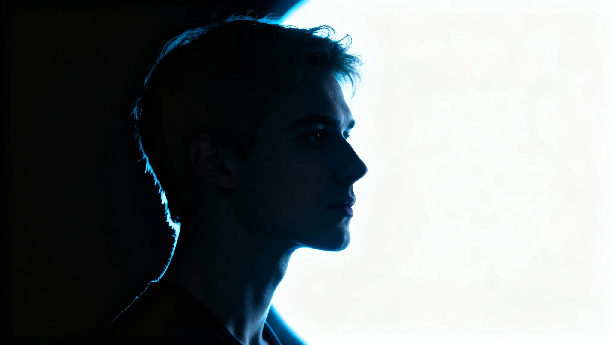 A dramatic studio portrait demonstrating rim lighting, where a bright light from behind creates a glowing outline of a person's silhouette against a dark background.