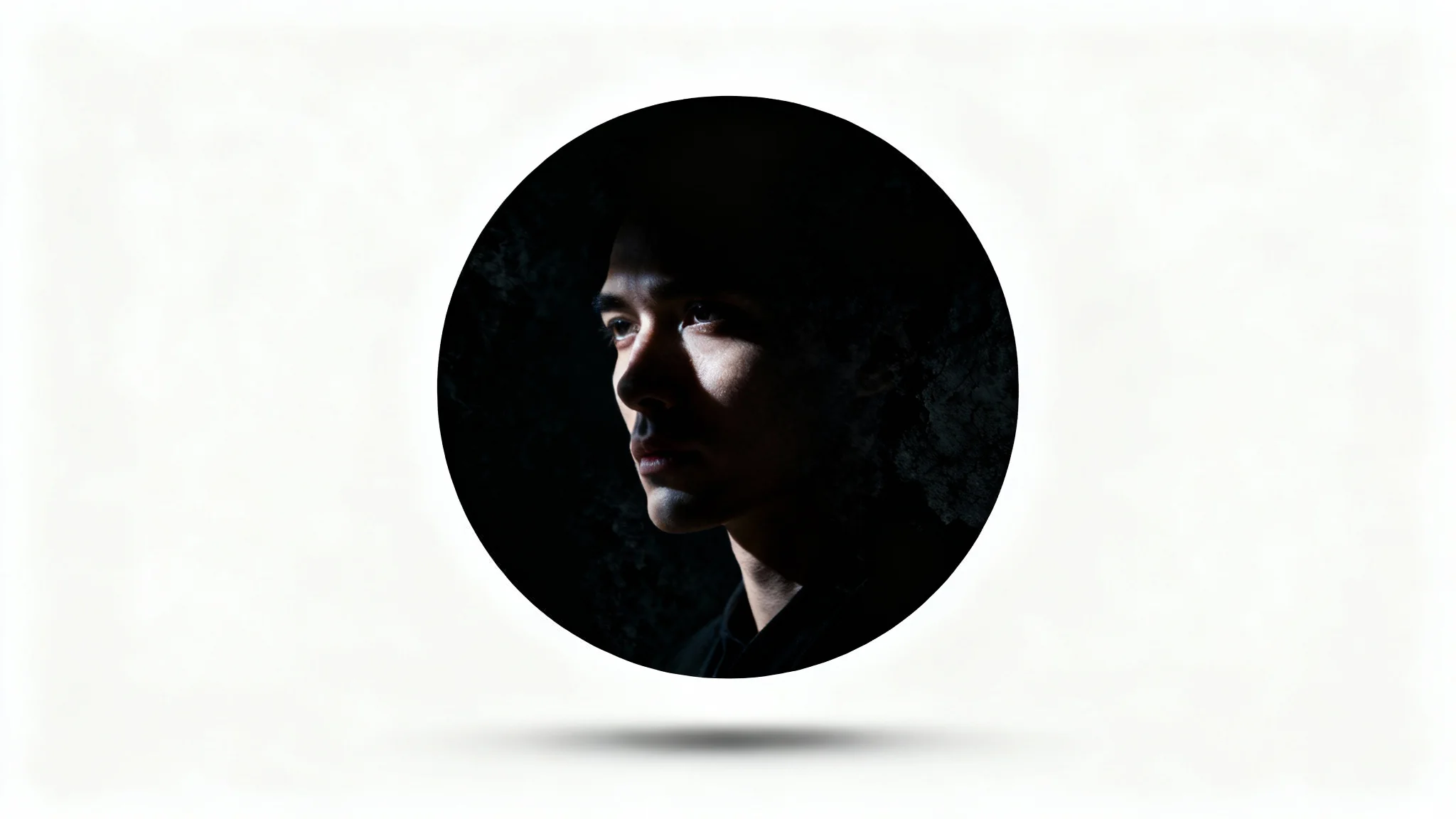 A mockup of a circular profile picture with a dark, moody aesthetic, displayed against a plain white background. The picture shows a high-contrast, shadowed face of a mysterious person.