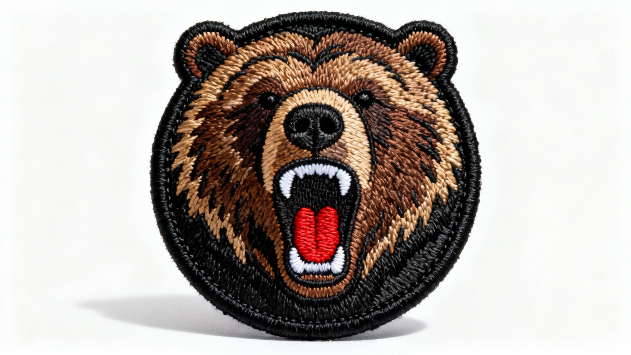 A photorealistic mockup of a circular embroidered patch featuring a detailed roaring grizzly bear head, displayed on a clean white background to showcase the embroidery quality.