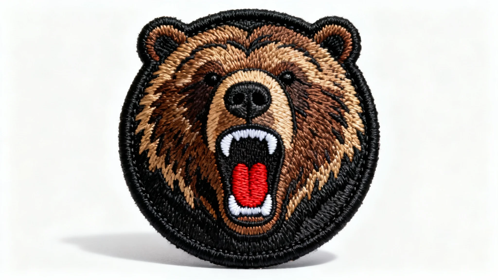 A photorealistic mockup of a circular embroidered patch featuring a detailed roaring grizzly bear head, displayed on a clean white background to showcase the embroidery quality.
