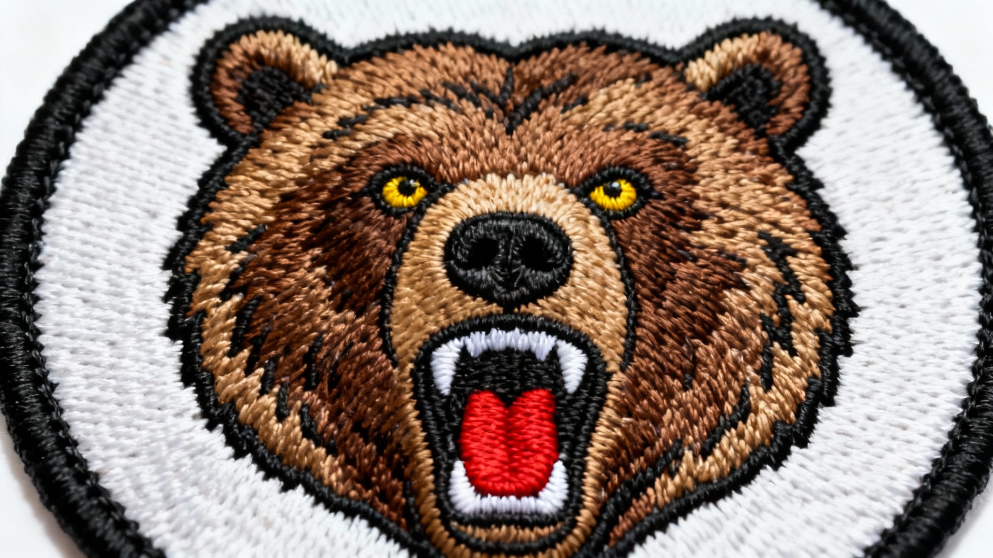 A photorealistic mockup of a circular embroidered patch featuring a detailed roaring grizzly bear head, set against a plain white background to showcase its quality and craftsmanship.