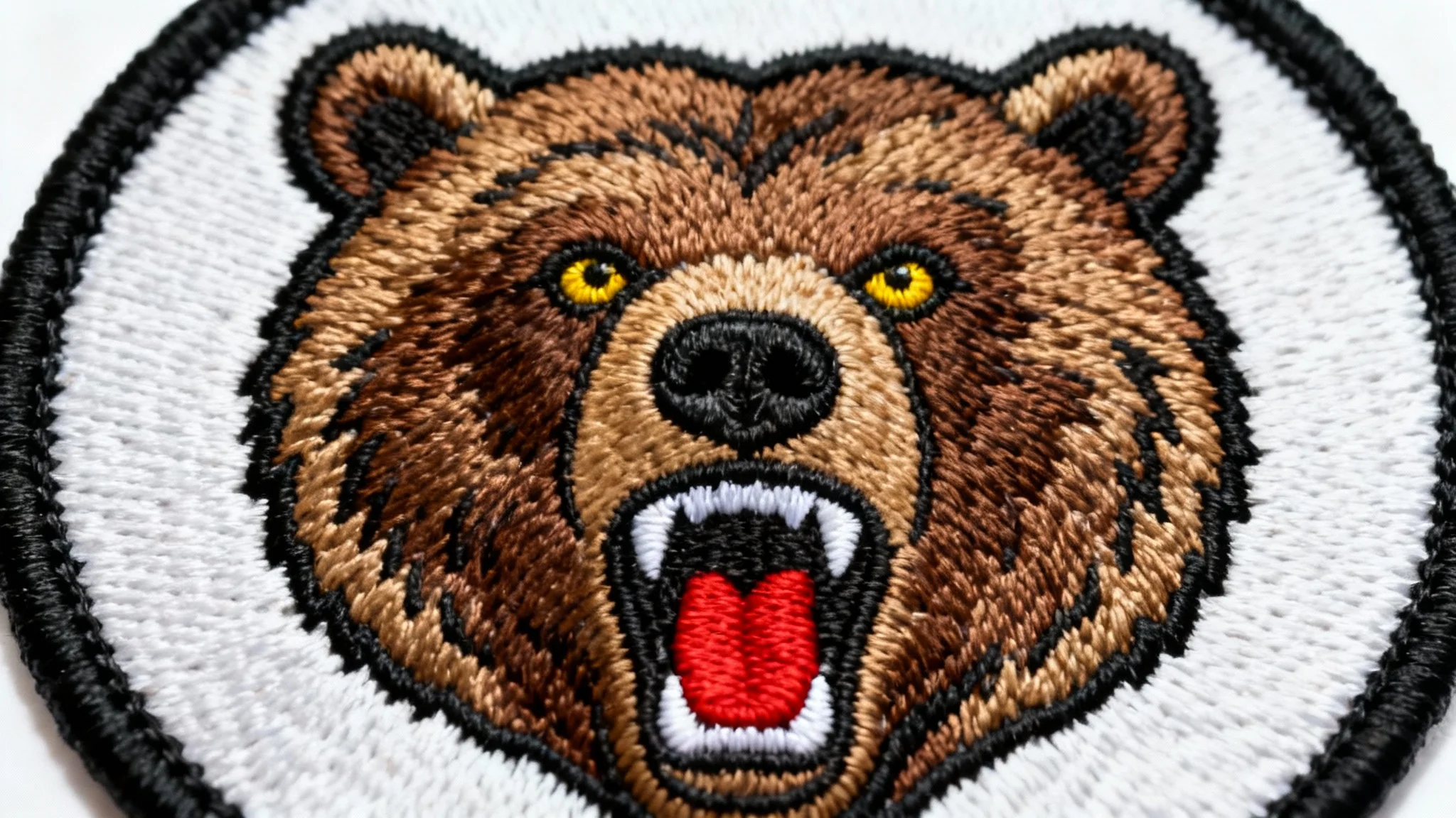 A photorealistic mockup of a circular embroidered patch featuring a detailed roaring grizzly bear head, set against a plain white background to showcase its quality and craftsmanship.