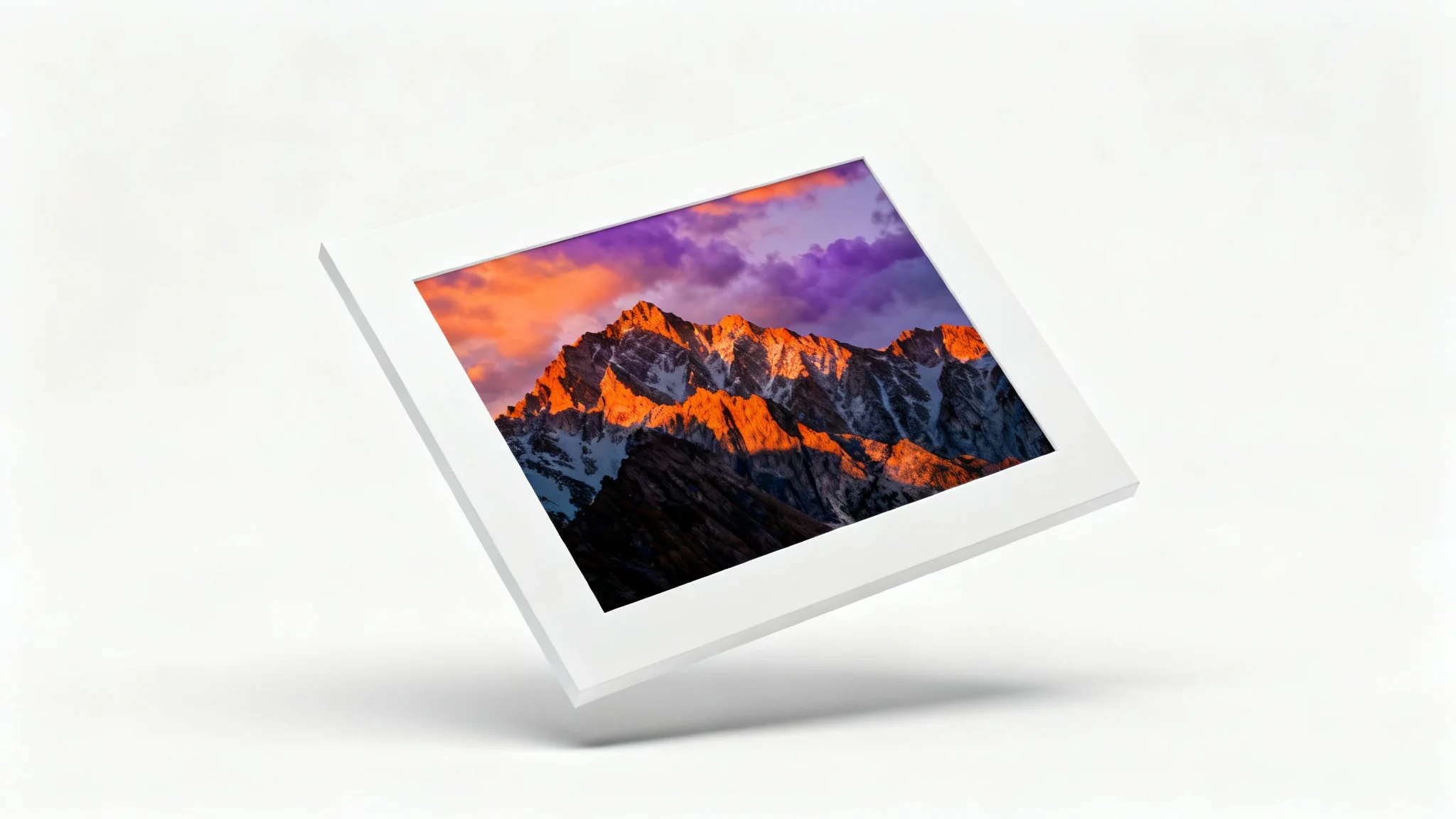 A photorealistic mockup of a landscape photograph of a mountain sunset, framed with a thick white border and displayed against a clean white background.