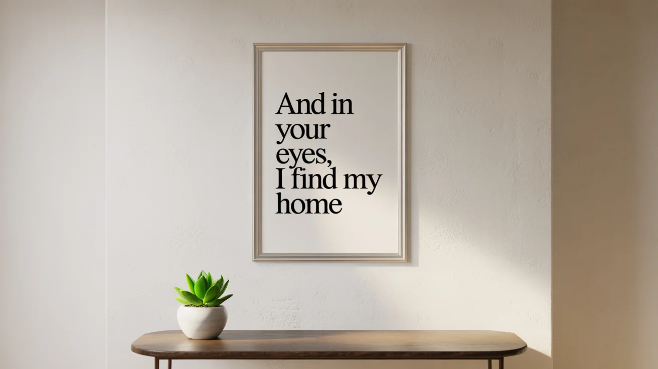 A framed poster with the words 'And in your eyes, I find my home' hanging on a modern wall above a small table with a plant.