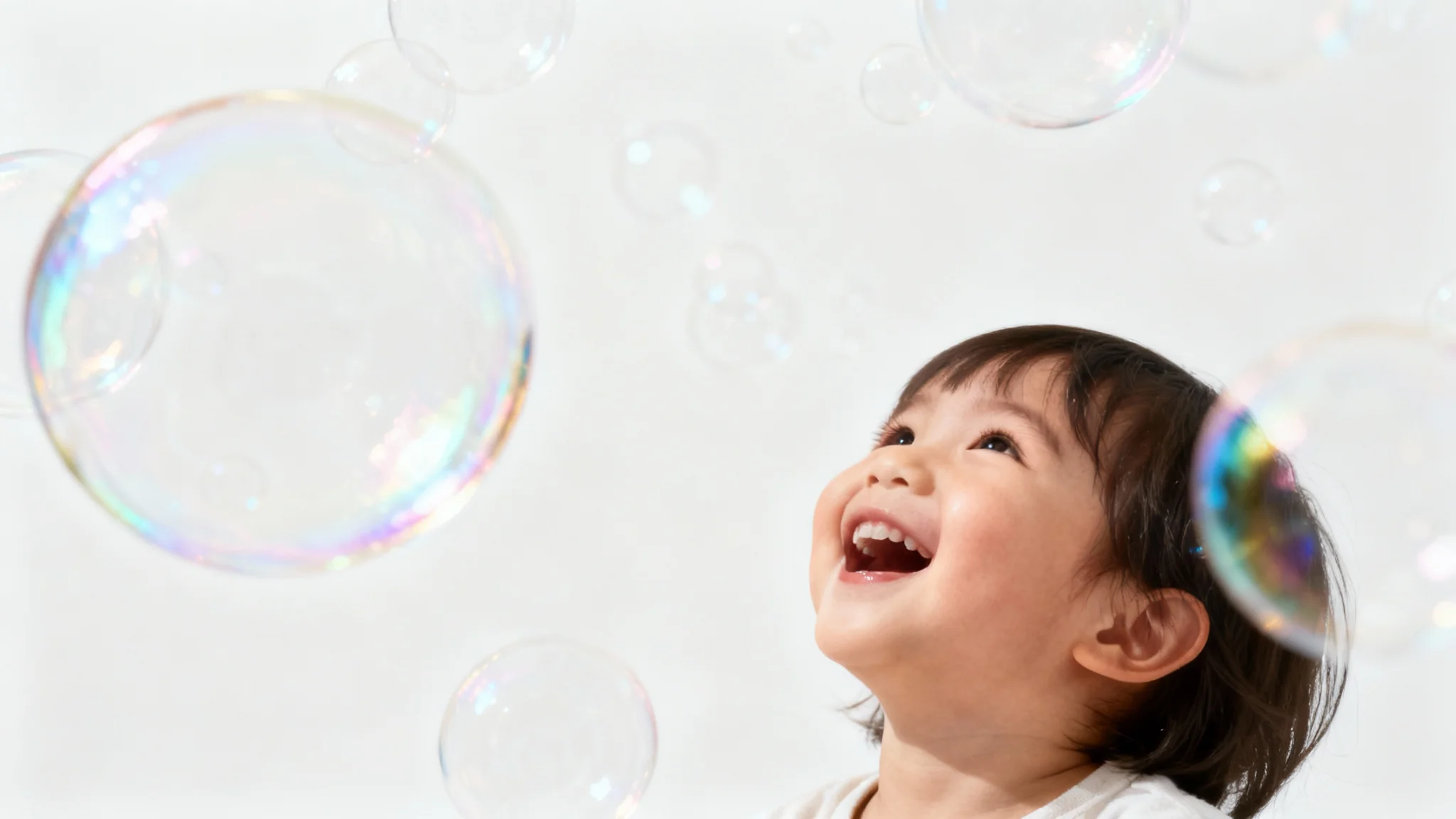 A photorealistic image of a happy child surrounded by a magical overlay of shimmering, multi-colored soap bubbles against a plain white background.