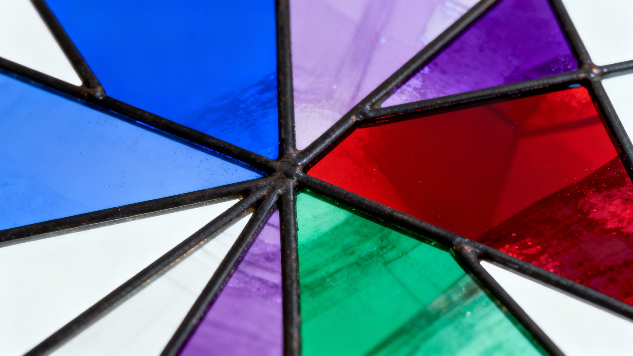 A vibrant stained glass panel with an abstract geometric pattern in jewel tones, shown against a clean white background.