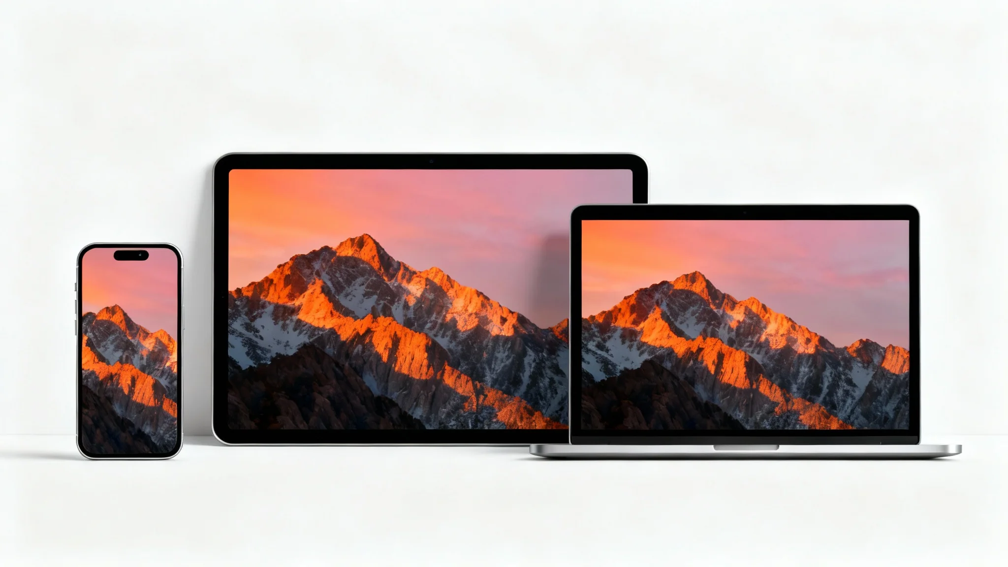 A smartphone, tablet, and laptop arranged on a white background, all displaying the same mountain sunrise wallpaper perfectly resized to fit each device's screen.