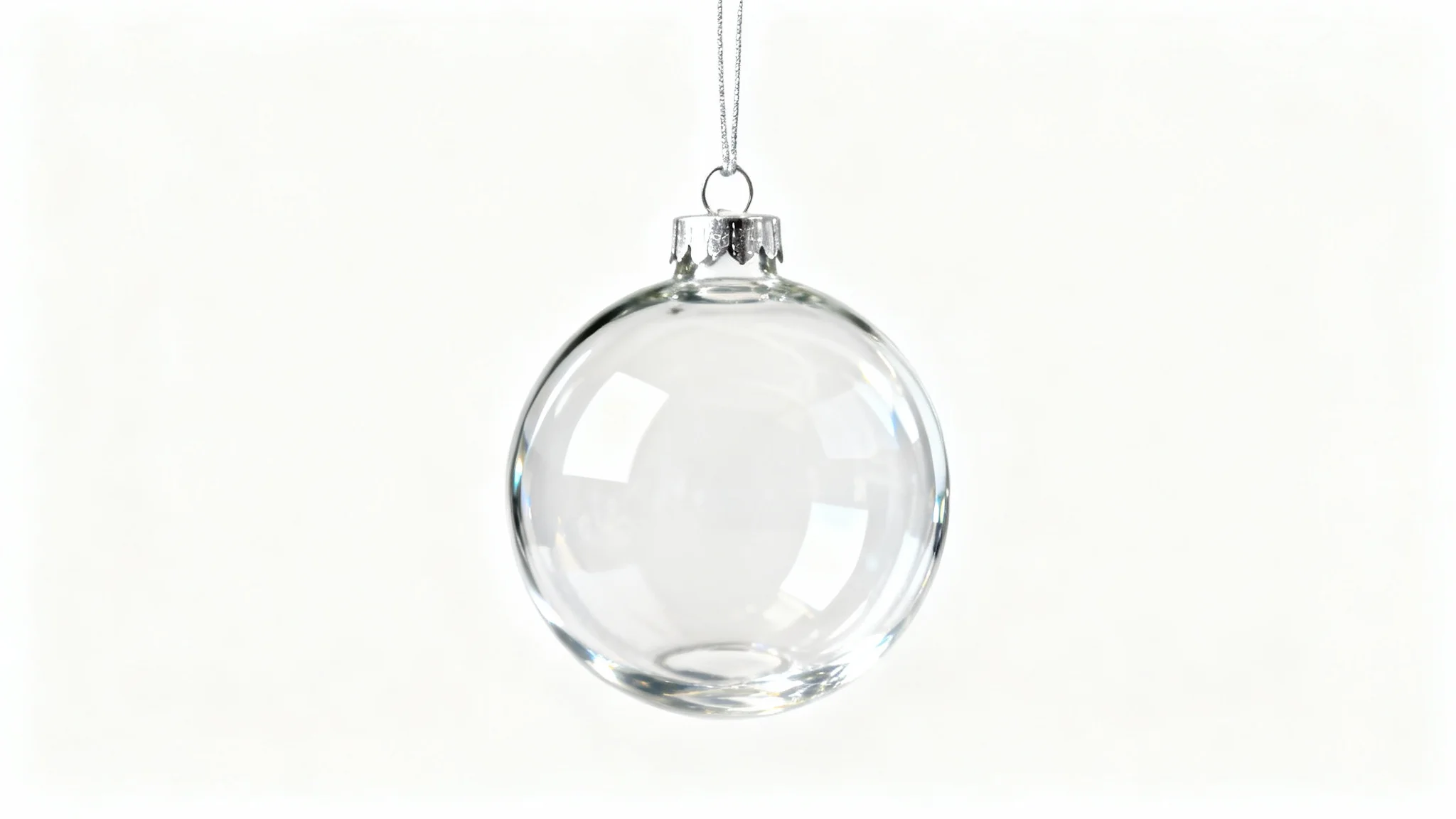 A close-up product photo of a single, perfectly clear, spherical glass Christmas ornament hanging against a solid white background, showcasing its minimalist and elegant design.
