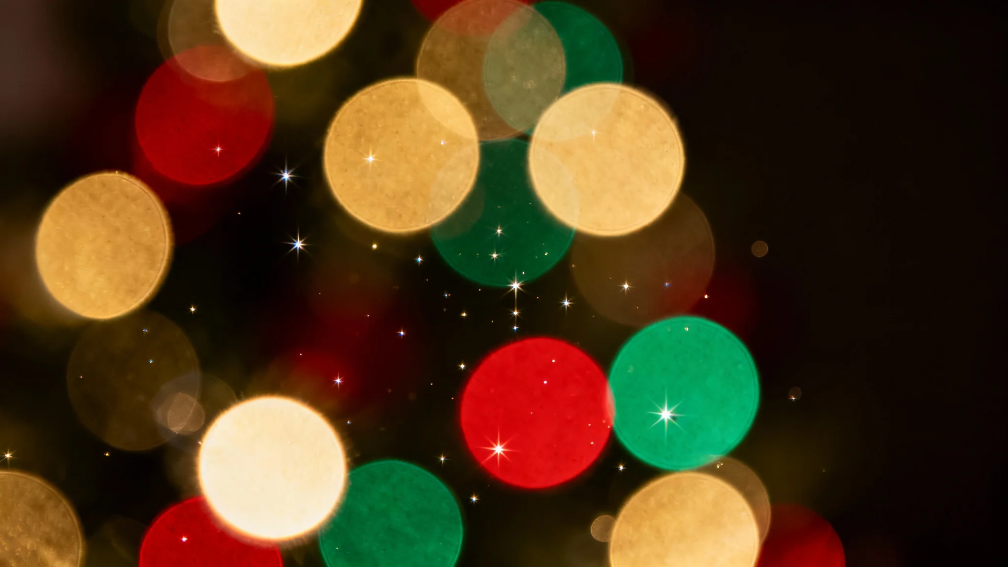 A festive Christmas bokeh background featuring soft, out-of-focus glowing orbs of light in gold, red, and green on a dark backdrop, creating a warm and magical holiday atmosphere.