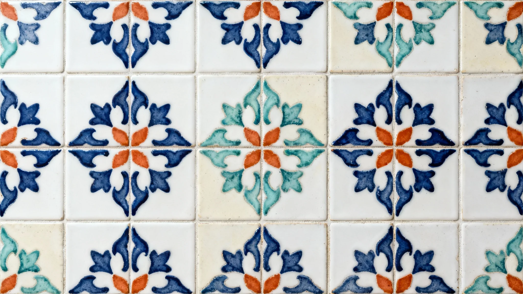A top-down view of a seamless tile pattern with Mediterranean-inspired geometric and floral designs in navy, terracotta, and seafoam green, set against a clean white background.