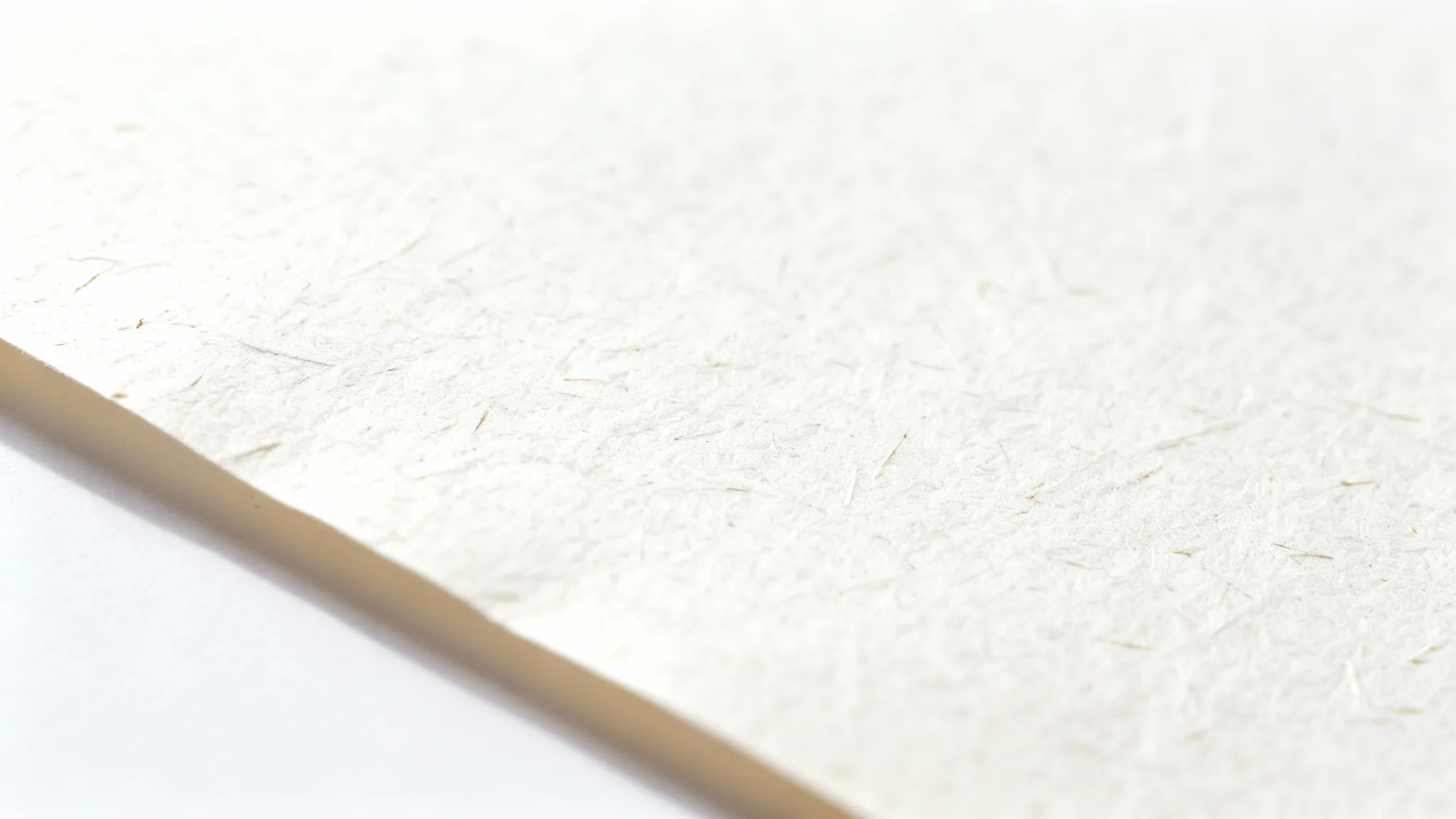 A detailed macro shot of a textured, off-white paper sheet, highlighting its fibrous composition, set against a clean white background.