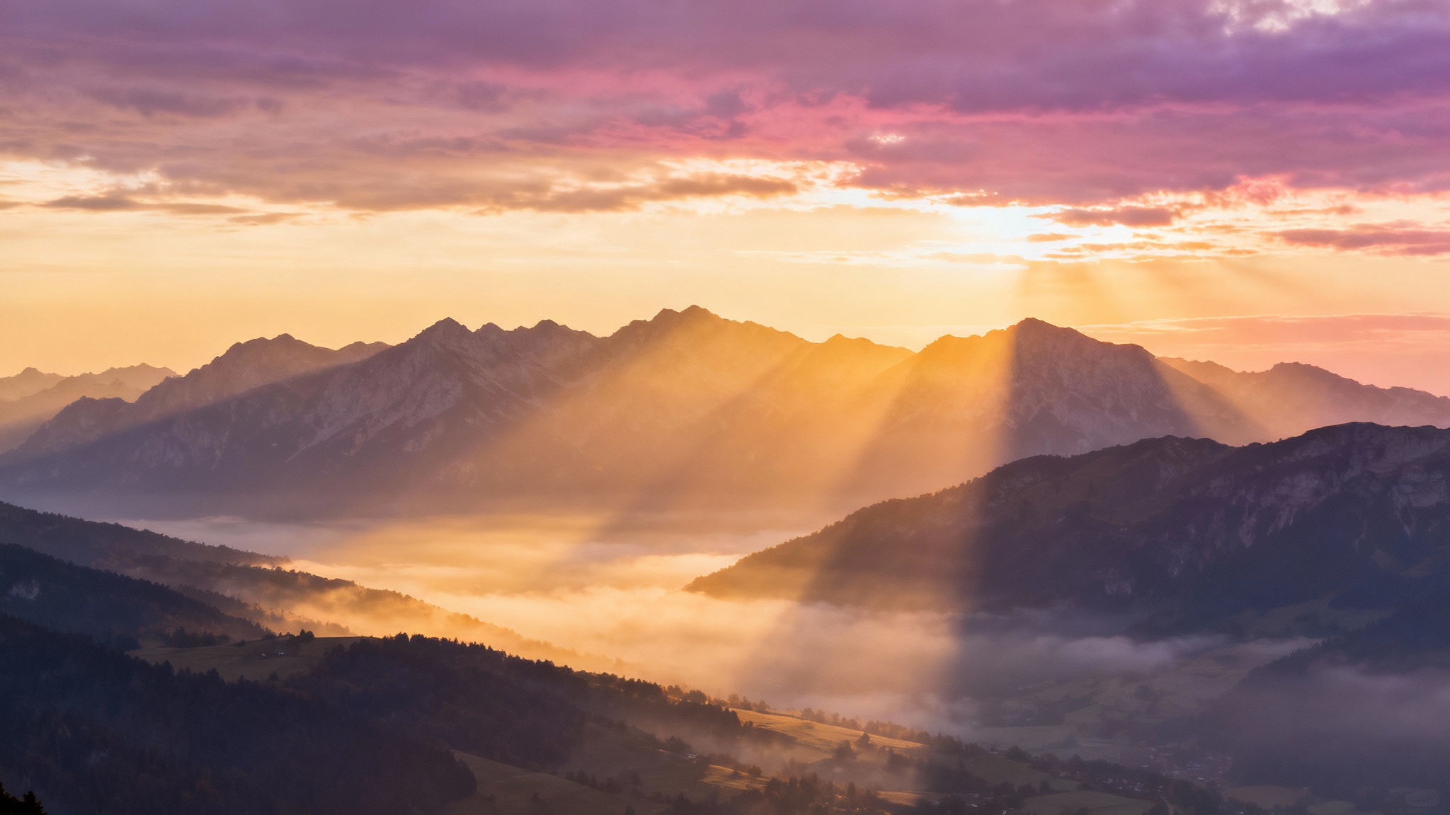 A serene sermon slide background depicting a majestic mountain range at sunrise, with golden sun rays breaking through the clouds.