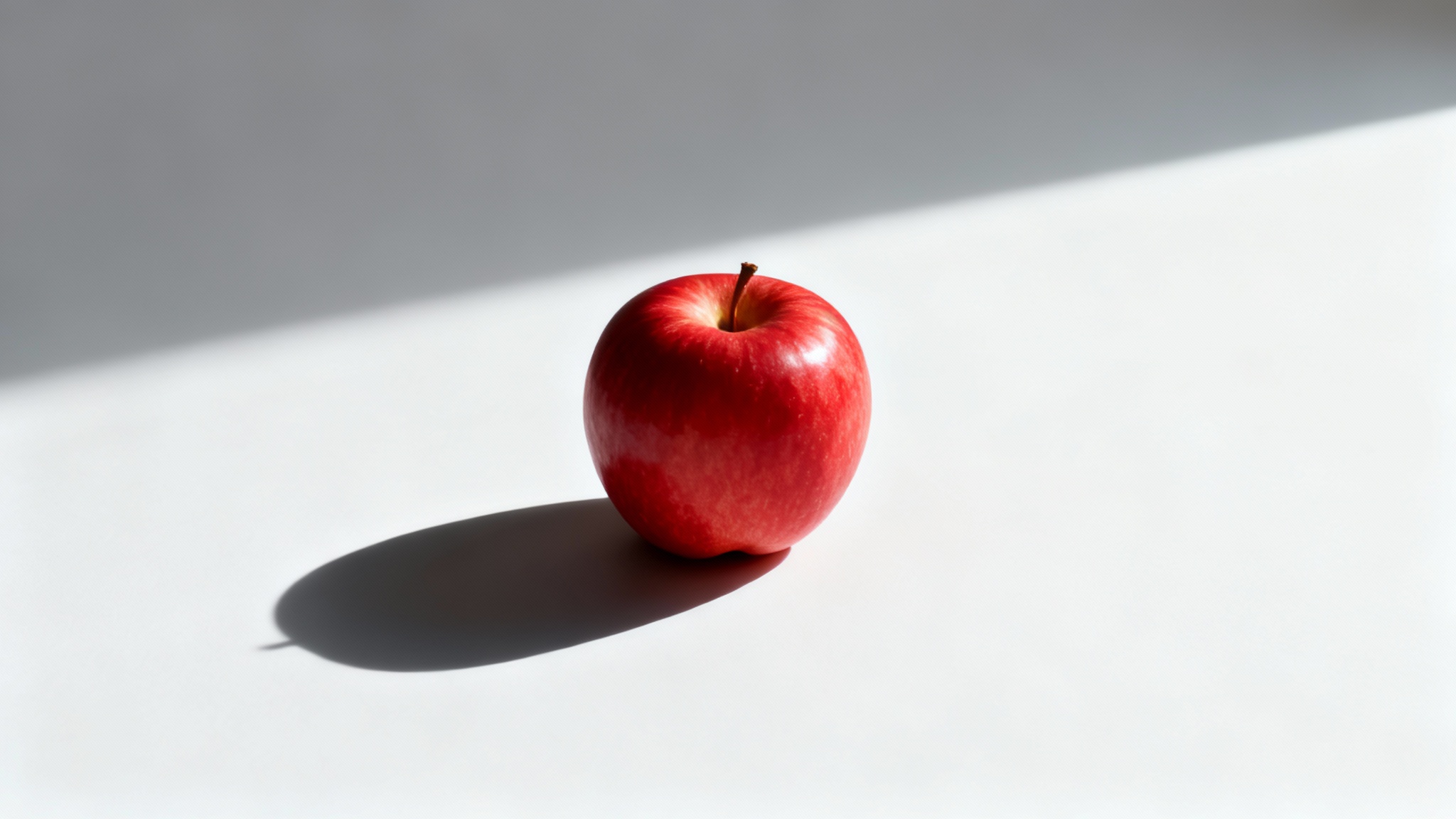 A photorealistic image of a single red apple on a white background, casting a sharp, clean shadow to its left, illustrating the 'add shadow' effect.