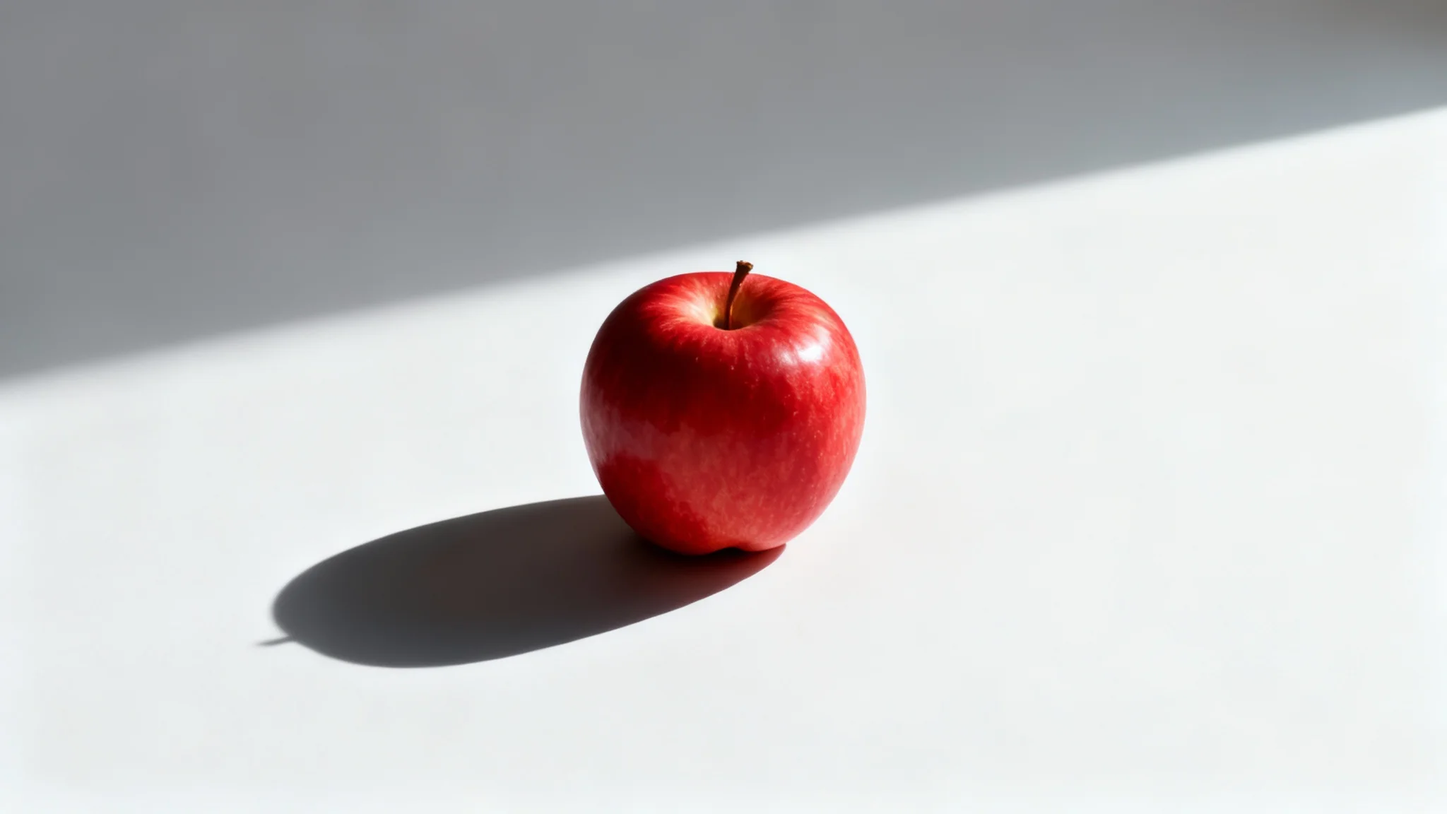A photorealistic image of a single red apple on a white background, casting a sharp, clean shadow to its left, illustrating the 'add shadow' effect.