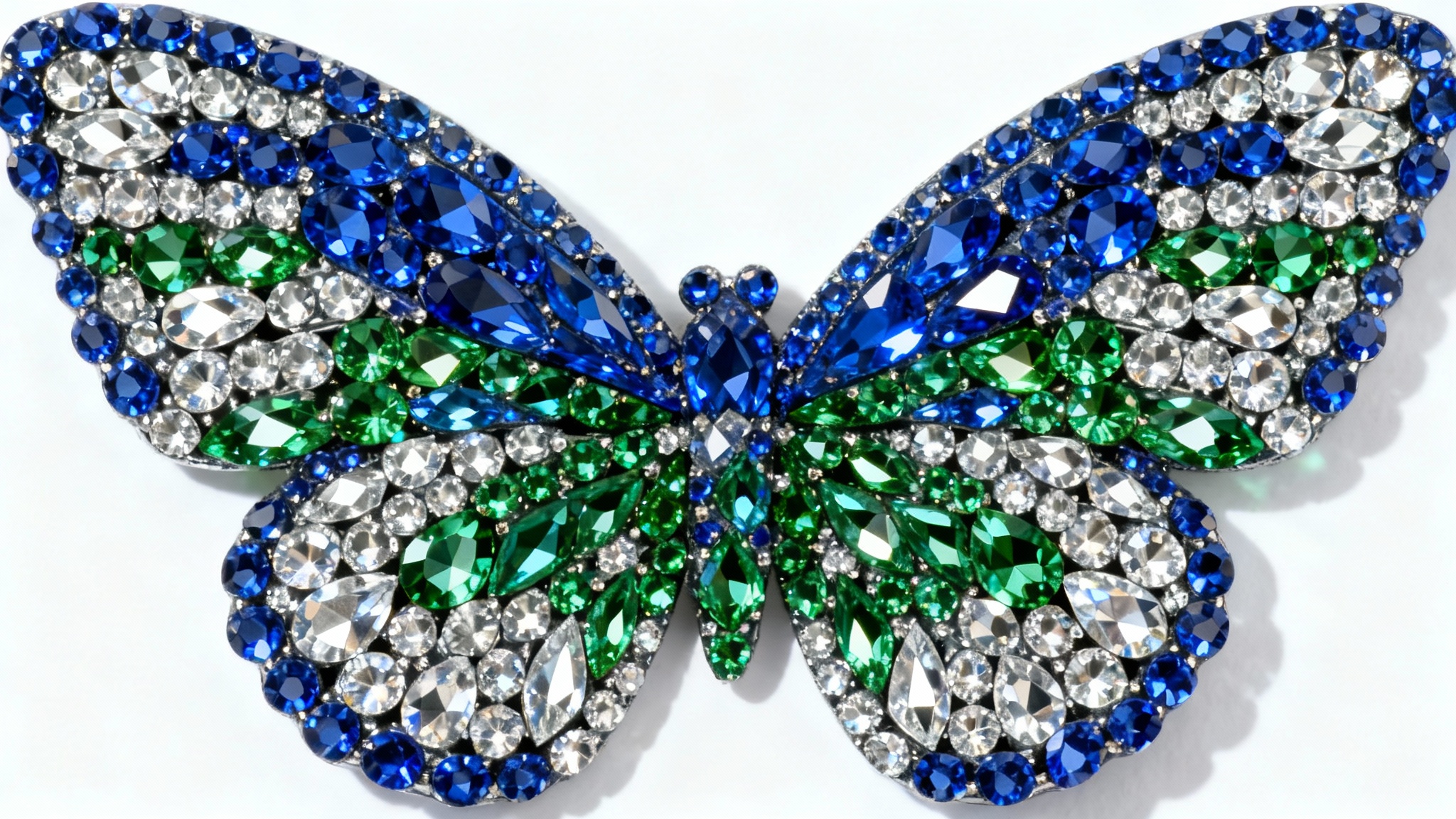 A hyper-detailed macro photograph of a butterfly pattern created with vibrant blue, green, and silver rhinestones, sparkling against a stark white background.