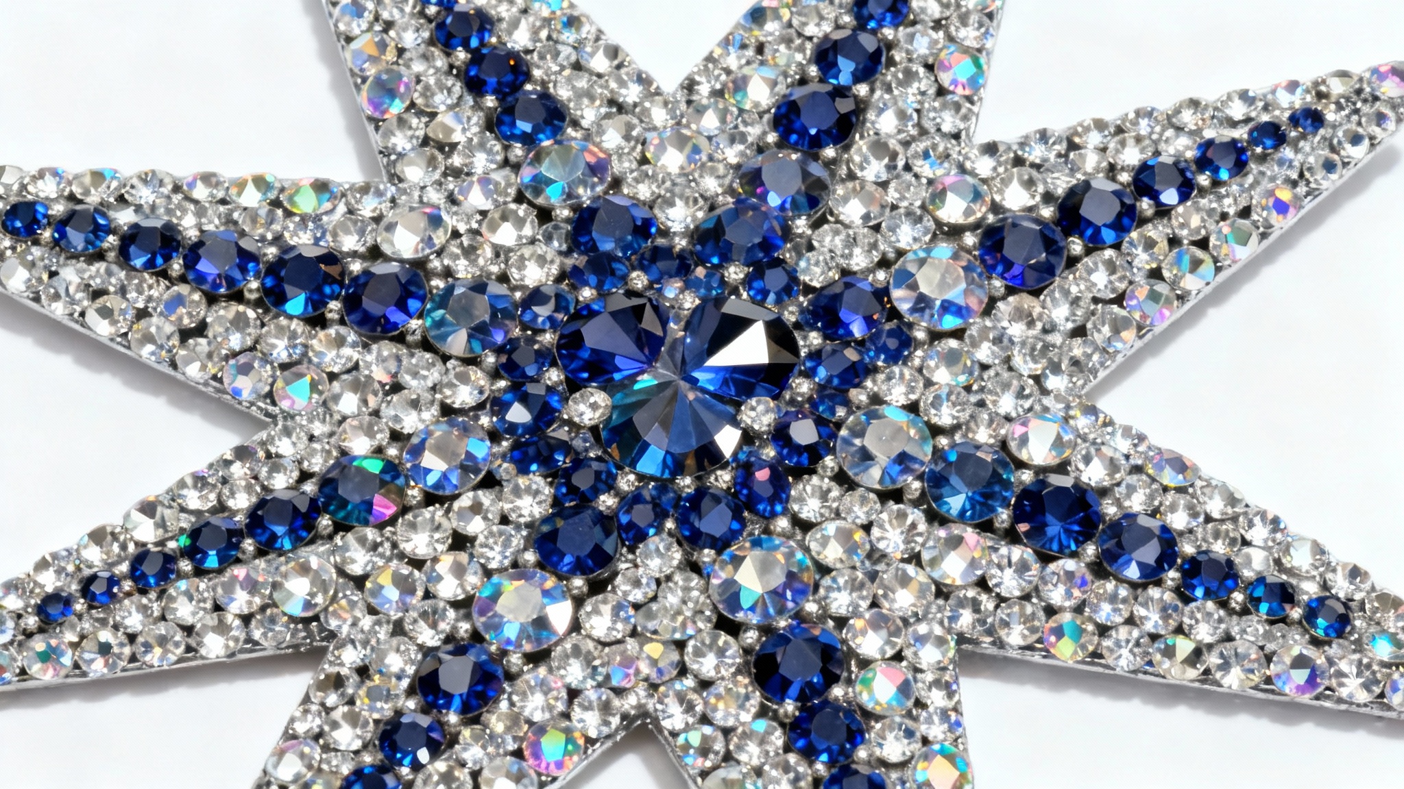 A photorealistic mockup of an intricate star-shaped pattern made from sparkling silver, blue, and iridescent rhinestones, shot from above on a clean white background.