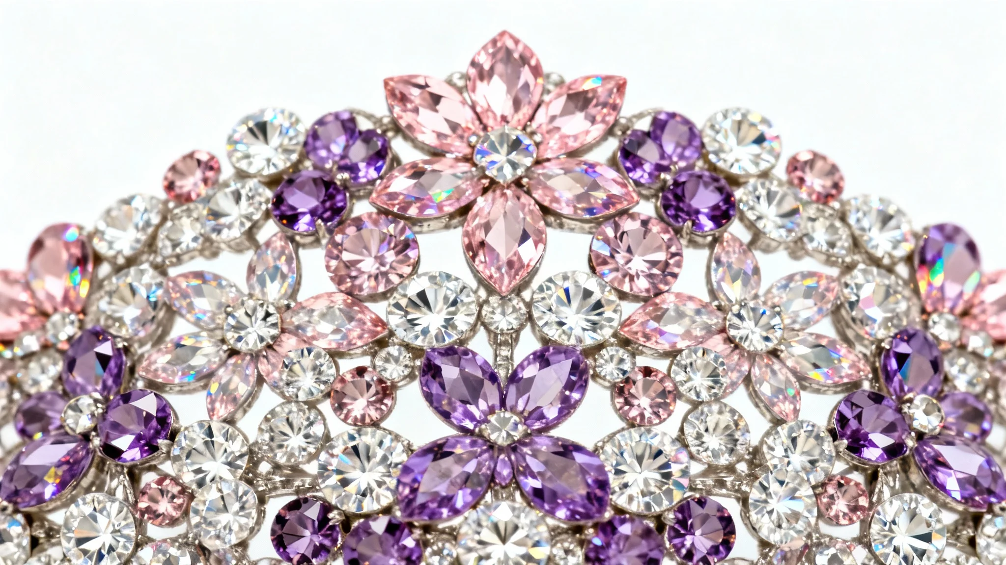 An extreme close-up of a beautiful floral pattern created with sparkling pink, purple, and clear rhinestones, set against a plain white background.