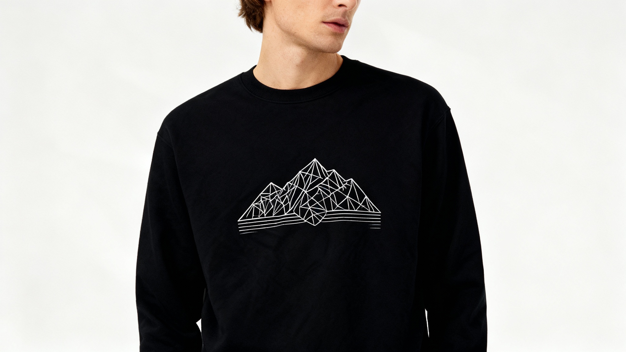A professionally shot mockup of a person wearing a black sweatshirt that has a custom white geometric mountain range design printed on the front.