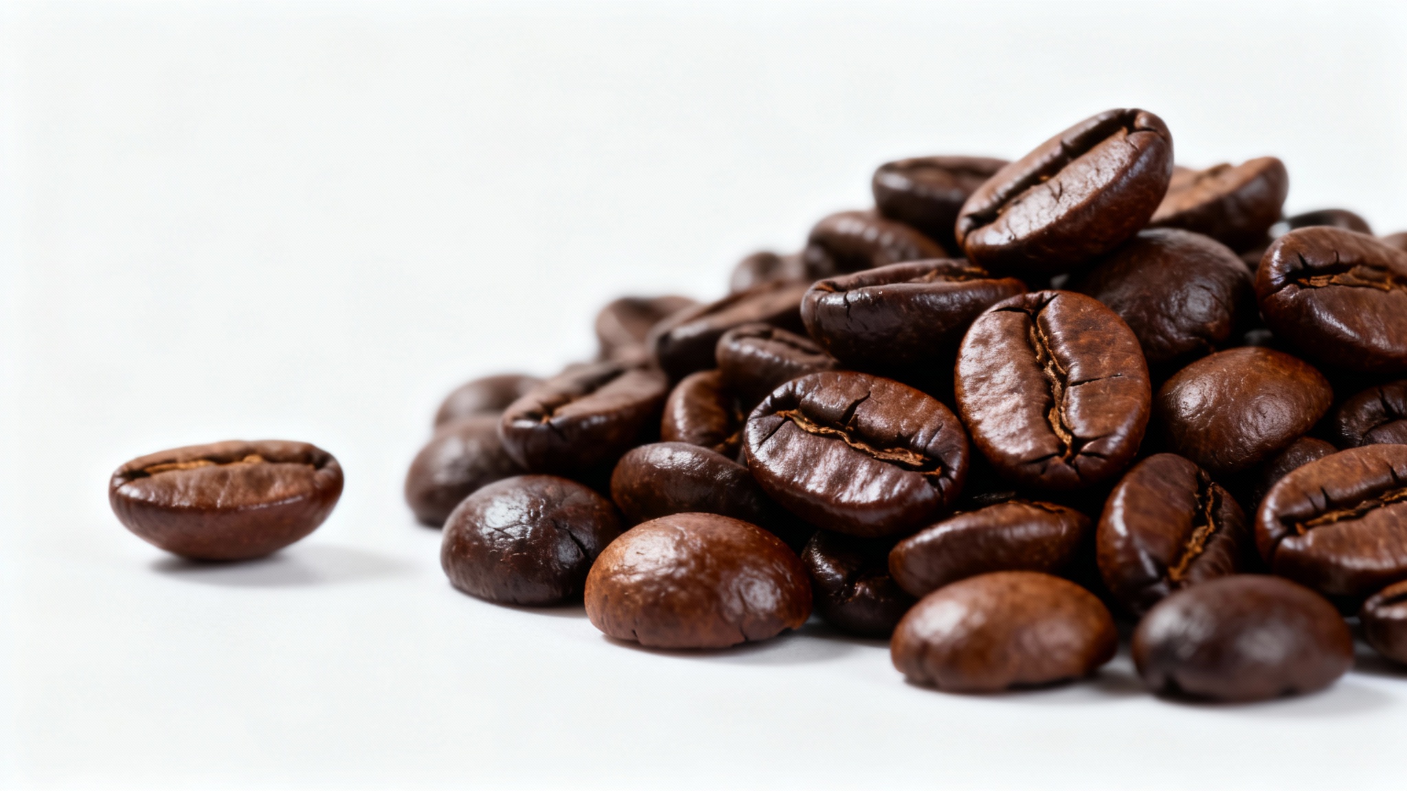 A close-up, professional photograph of freshly roasted, glossy coffee beans piled on a clean white background.