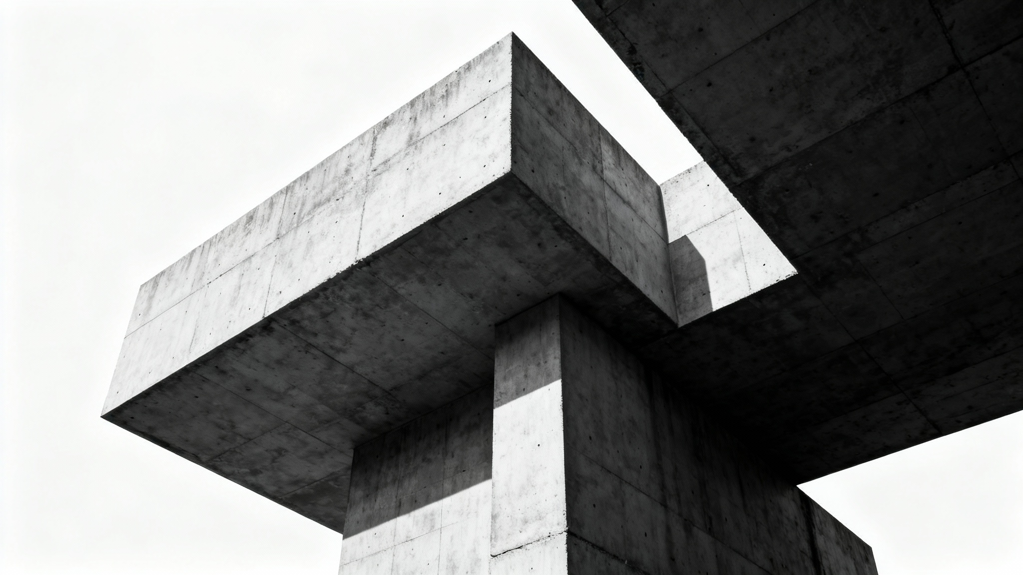 A dramatic low-angle photograph of a massive brutalist building, showcasing its raw concrete texture and bold geometric forms against a plain white background.
