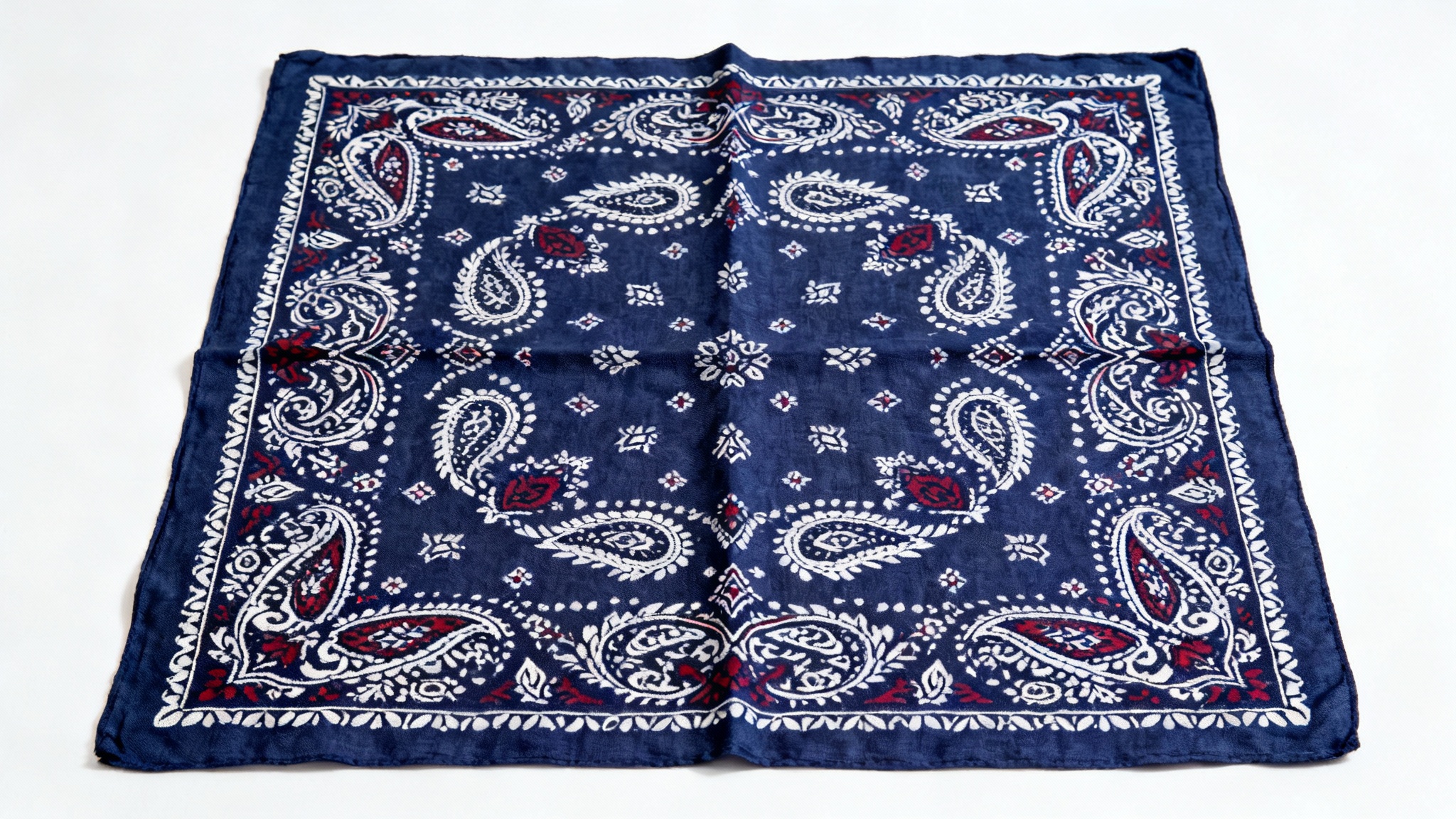 A photorealistic mockup of a navy blue bandana with a detailed white and crimson paisley pattern, laid flat on a white background.