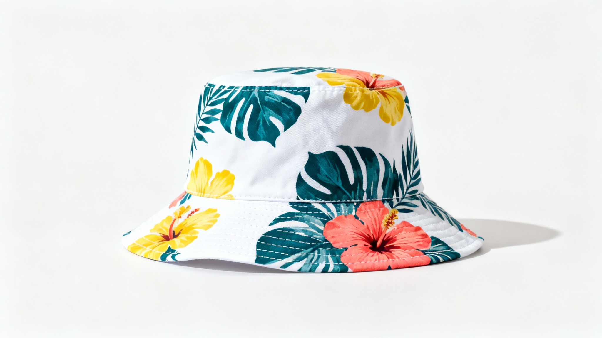 A photorealistic mockup of a white bucket hat featuring a colorful tropical leaf and flower pattern, presented on a plain white background.