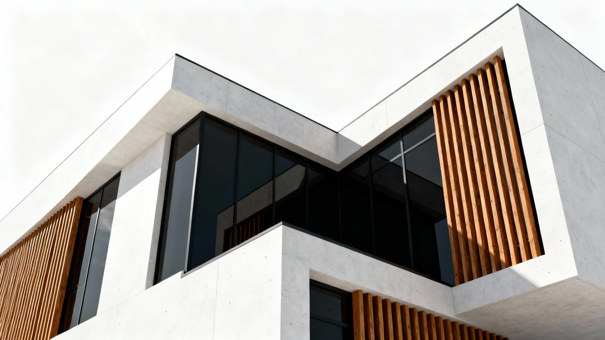 A low-angle view of a modern building's facade, showcasing a minimalist design with concrete, glass, and wood, set against a clean white background.