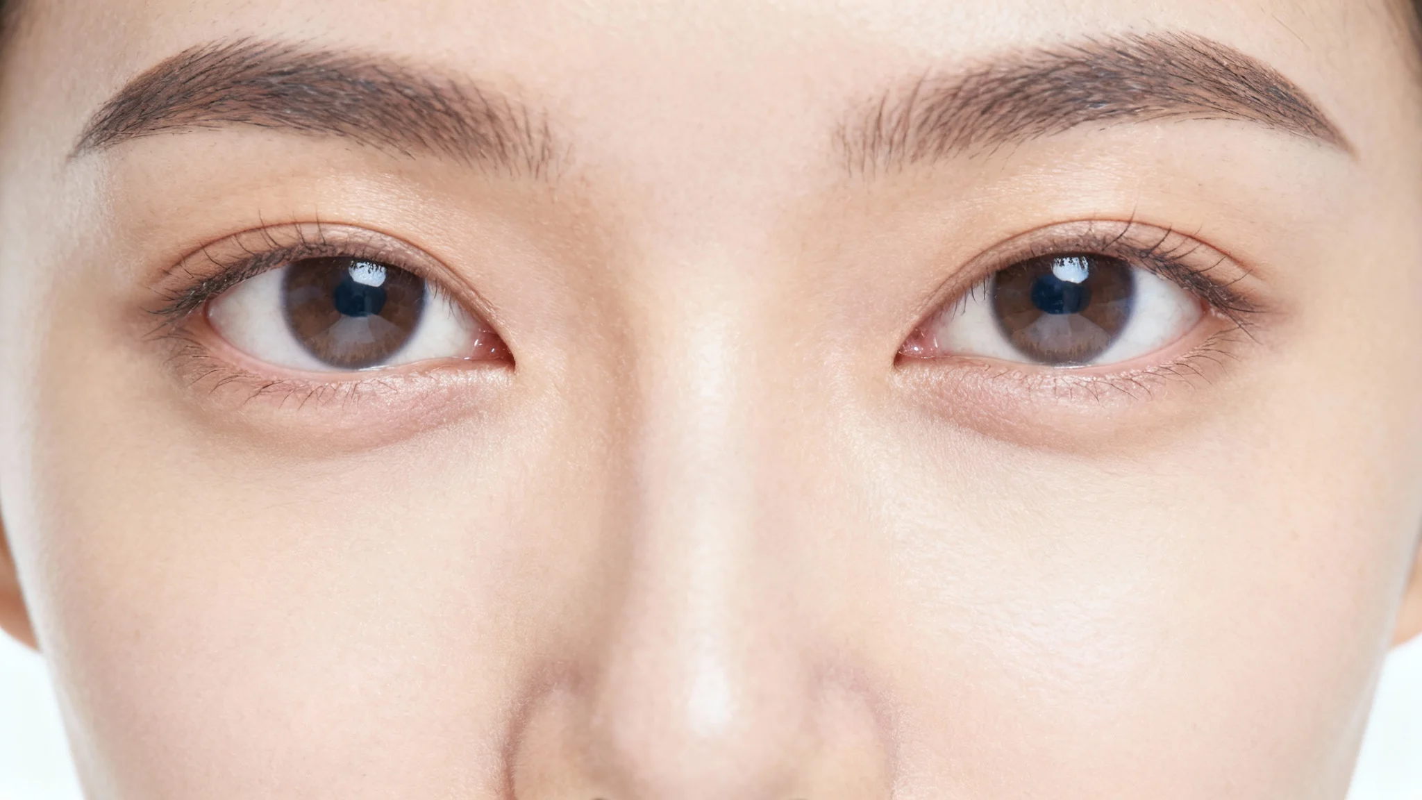 A photorealistic close-up of a woman's eye area, showing her face without any eyelashes on the upper or lower lids, against a stark white background.