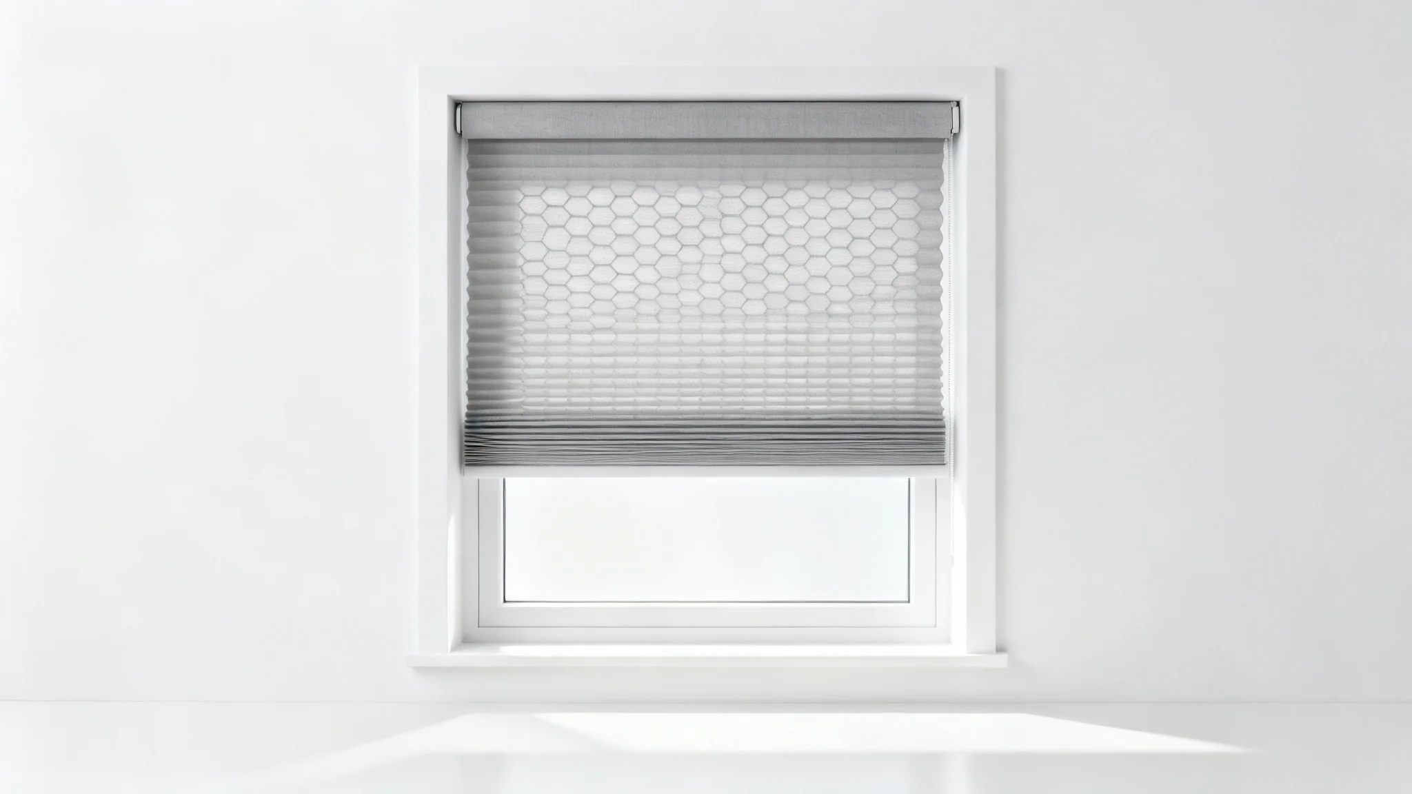 A studio-style mockup of a modern window featuring light gray cellular shades against a clean white wall, emphasizing a sleek and minimalist design.