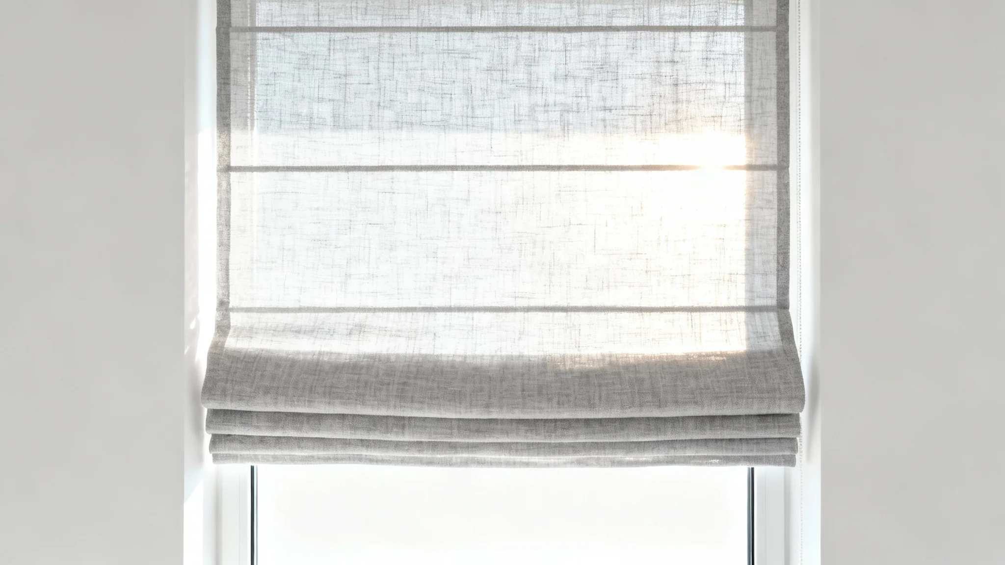 A minimalist mockup of an elegant, light-gray linen Roman shade against a white background, with soft sunlight filtering through to create a warm and serene ambiance.