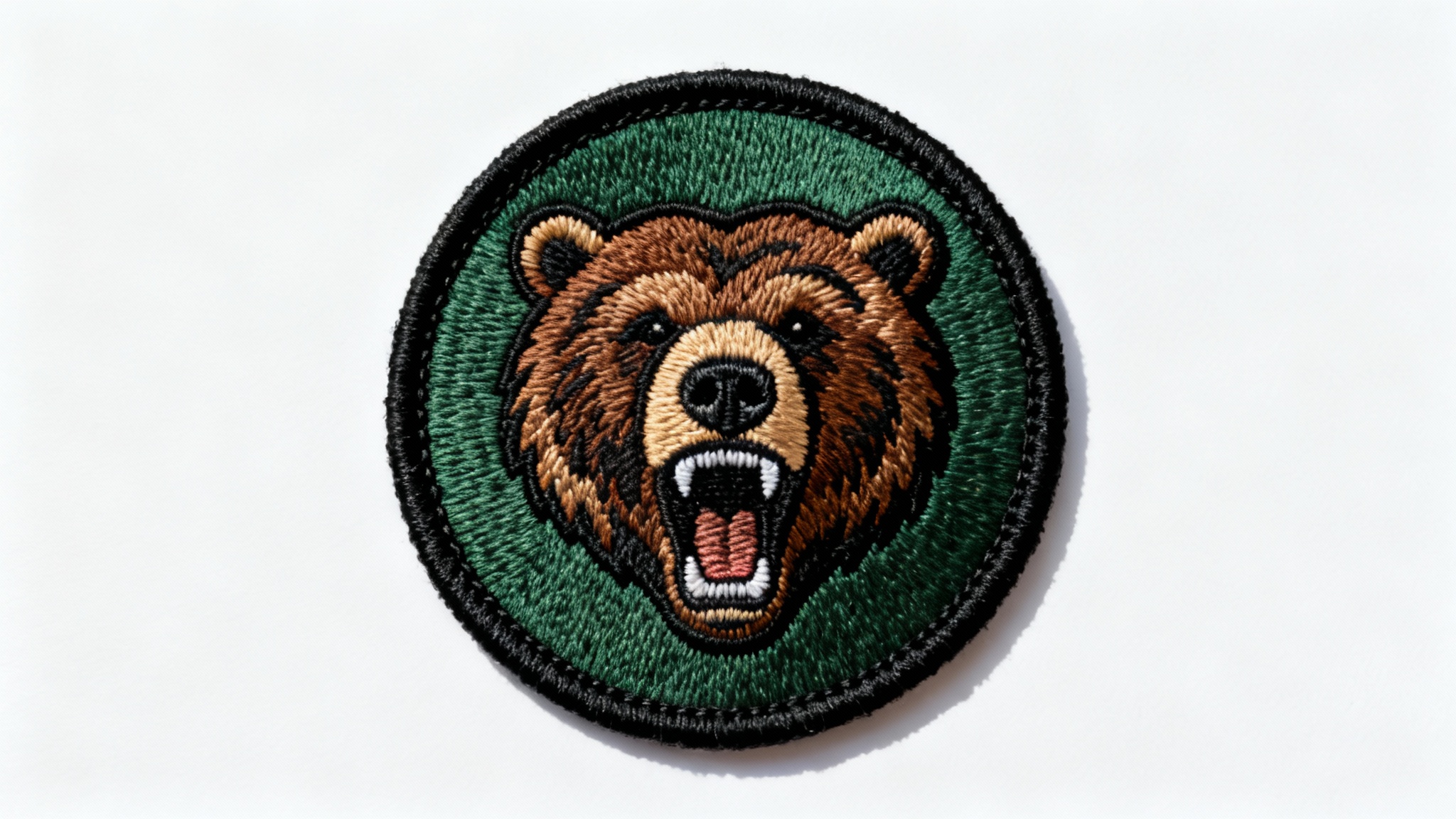 A high-resolution mockup of a circular embroidered patch featuring a detailed grizzly bear head, set against a plain white background.