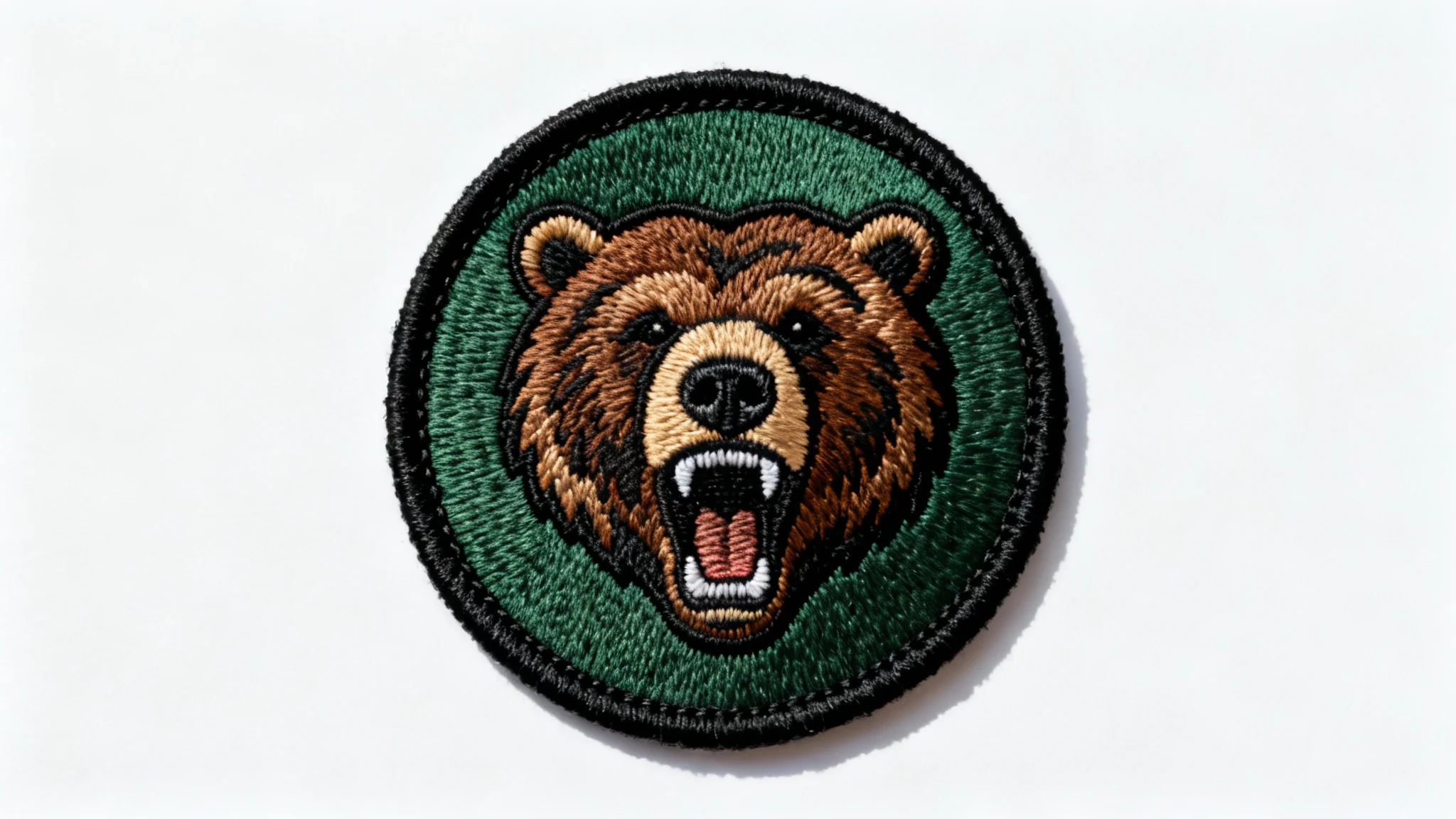 A high-resolution mockup of a circular embroidered patch featuring a detailed grizzly bear head, set against a plain white background.