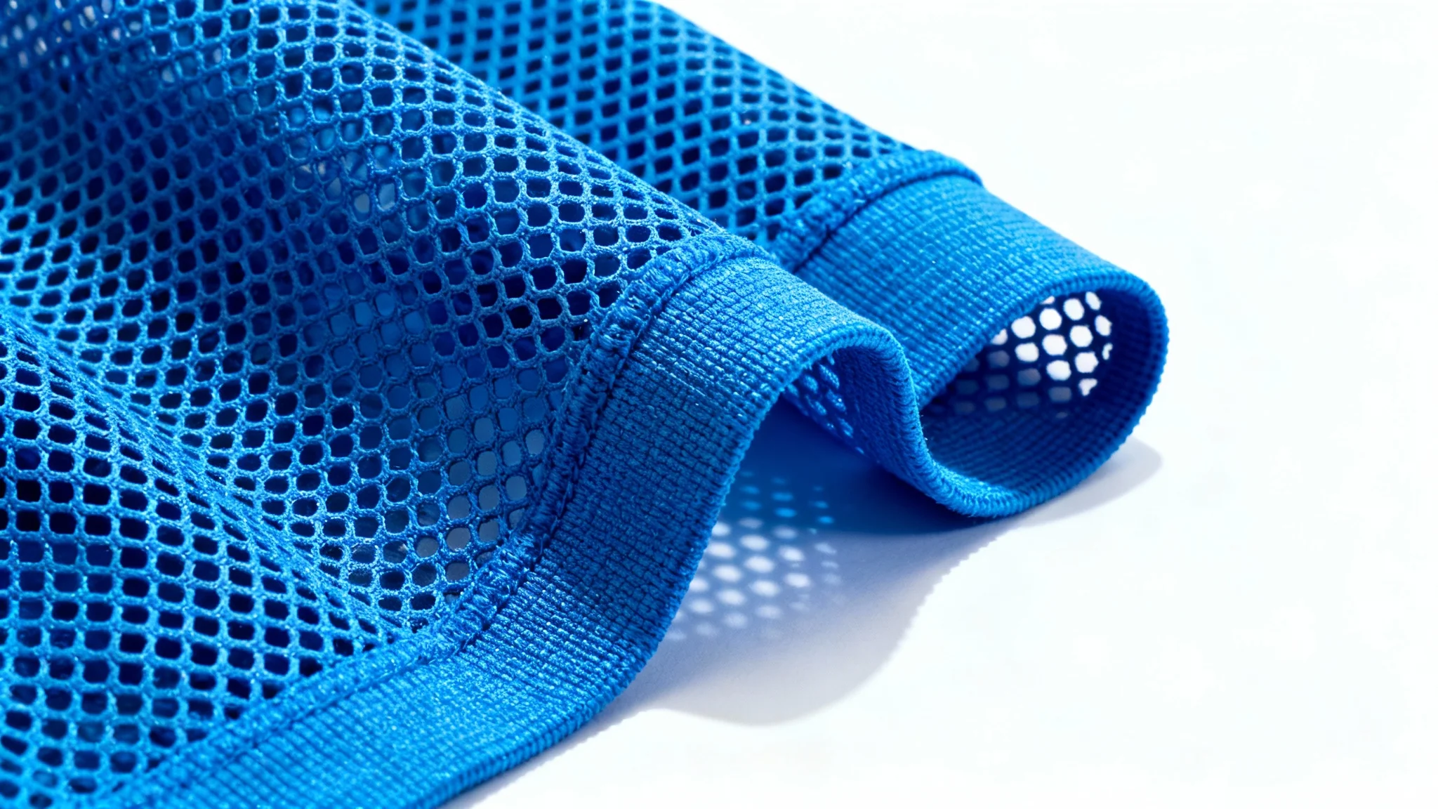 A detailed macro shot of a blue athletic mesh fabric, highlighting its hexagonal weave and texture against a stark white background.