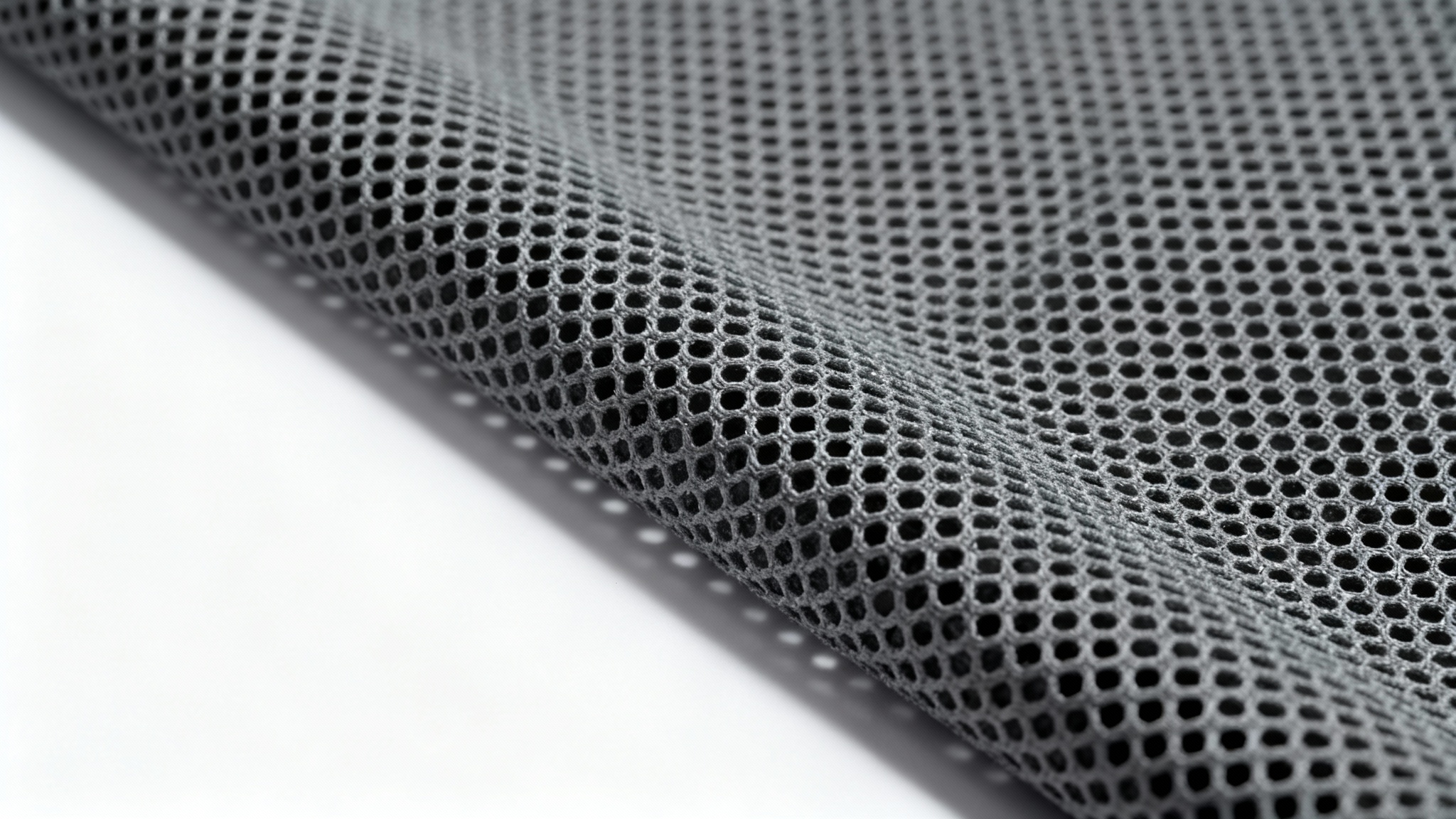 An extreme close-up, photorealistic image of a gray technical mesh fabric, highlighting its hexagonal pattern and texture, presented against a clean white background.