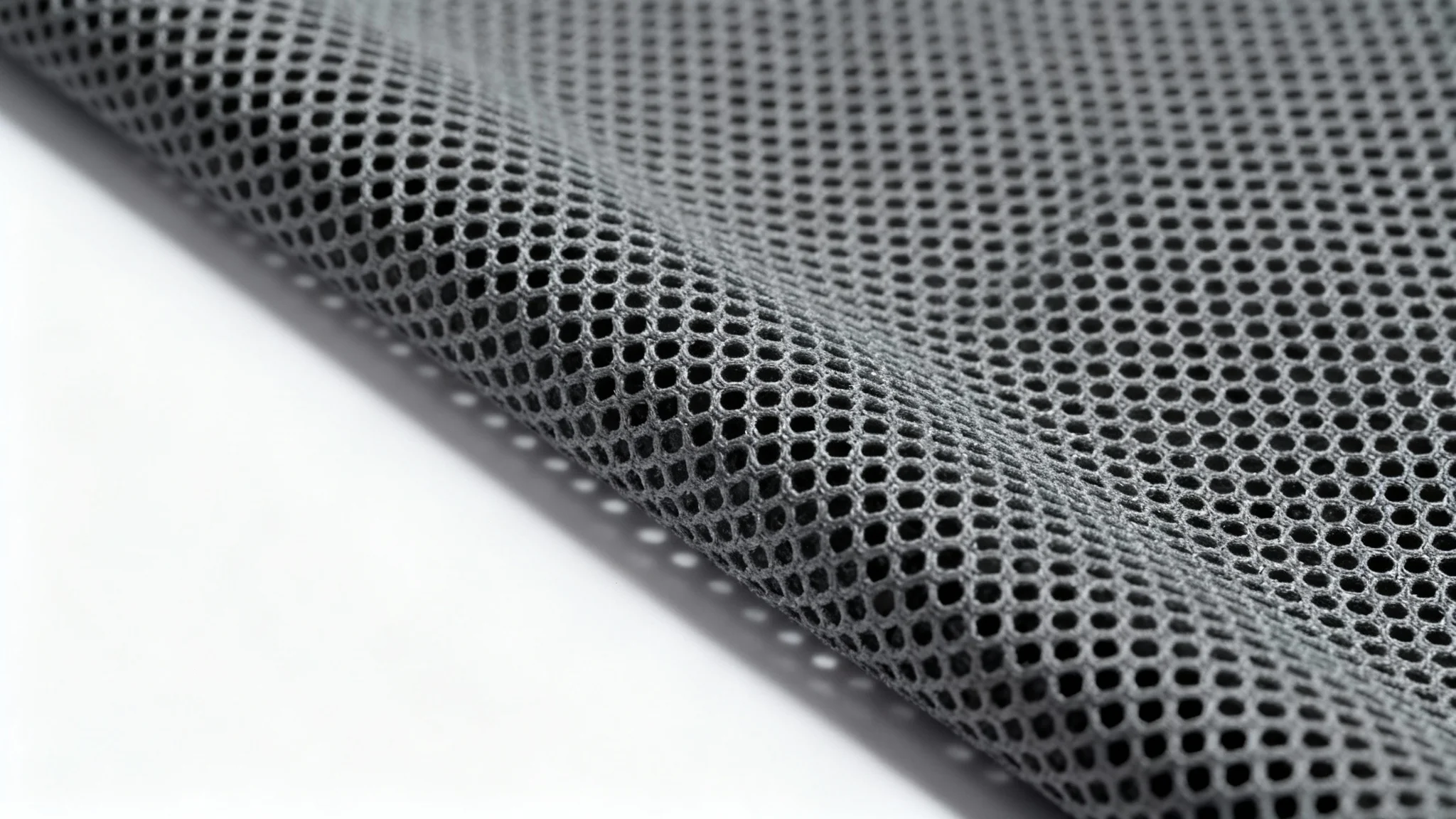 An extreme close-up, photorealistic image of a gray technical mesh fabric, highlighting its hexagonal pattern and texture, presented against a clean white background.