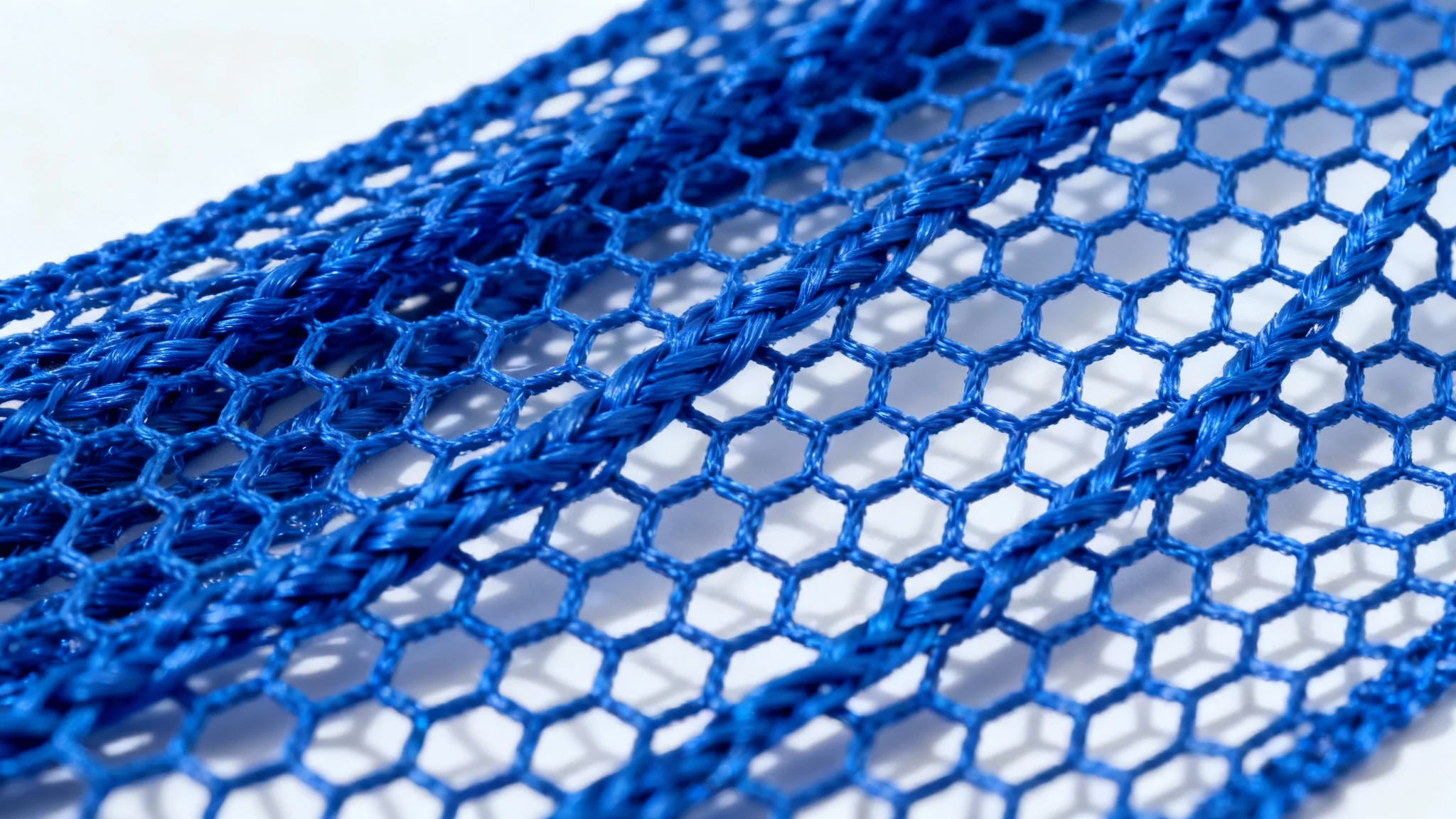 A hyper-detailed macro shot of a royal blue mesh fabric, showcasing the intricate hexagonal weave and texture against a clean white background.