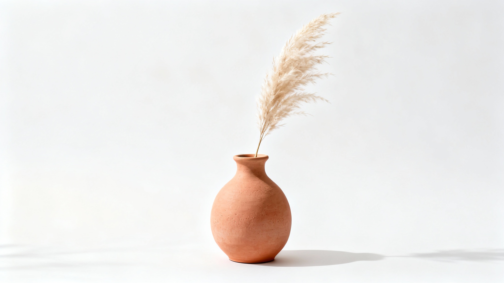 A professional product photograph of a terracotta-colored ceramic vase with a sprig of pampas grass, shot against a clean white background in a minimalist style for an Etsy listing.