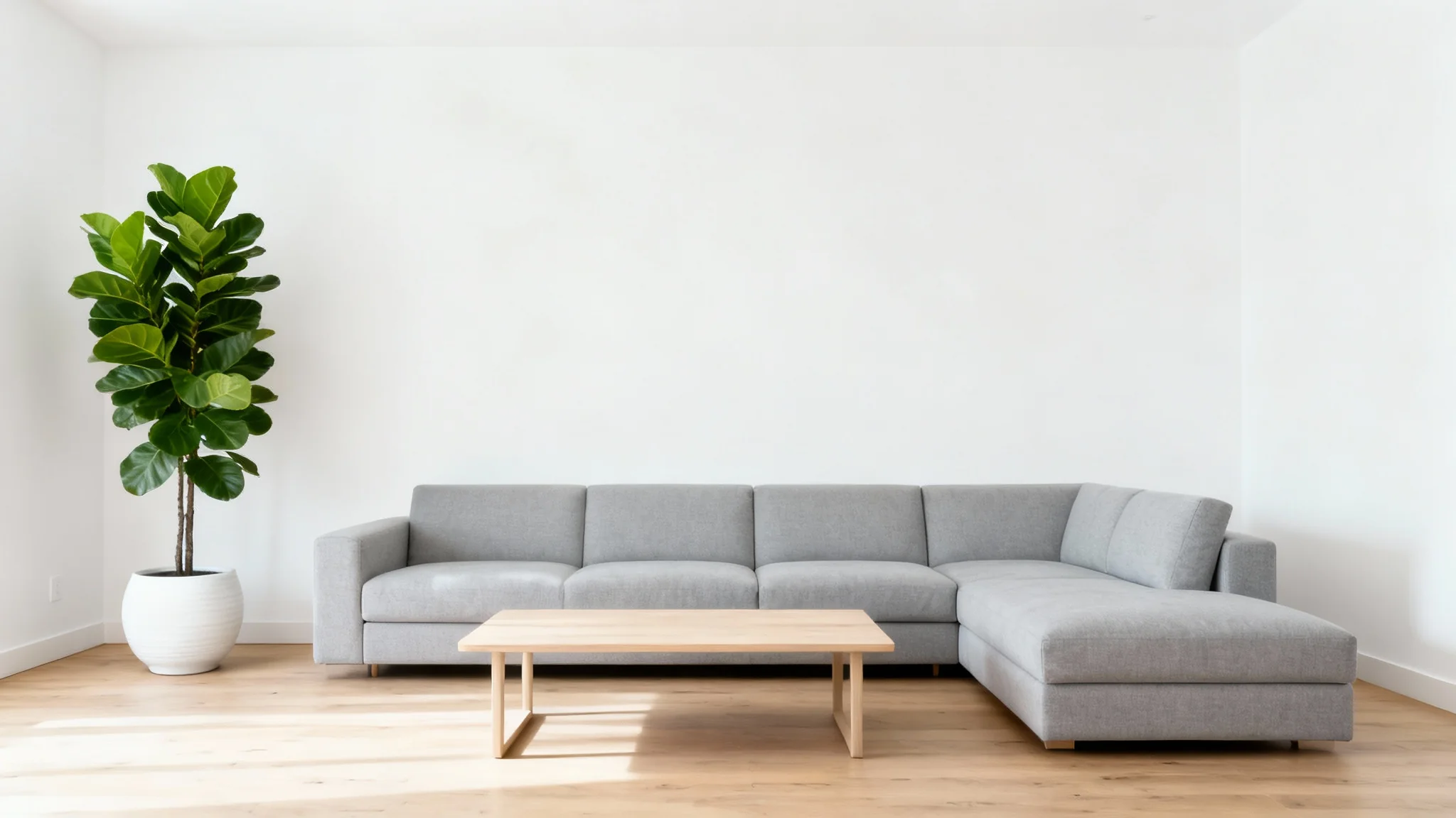 A beautifully remodeled, modern living room with white walls, light wood floors, a stylish gray sofa, and a large green plant in the corner, conveying a sense of bright, open space.