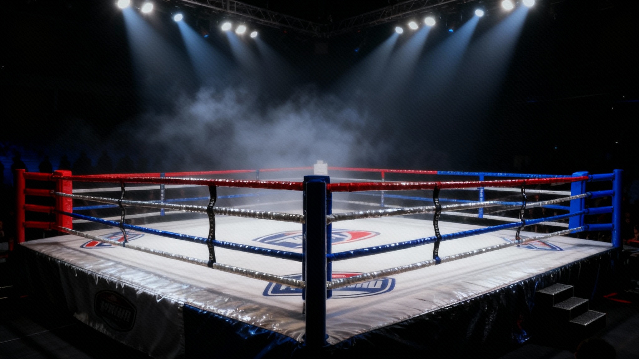 A dramatic, cinematic hero image of an empty boxing ring, viewed from a low angle. Bright spotlights shine down, creating beams of light in a hazy arena, highlighting the red and blue ropes and the empty canvas, ready for a fight.