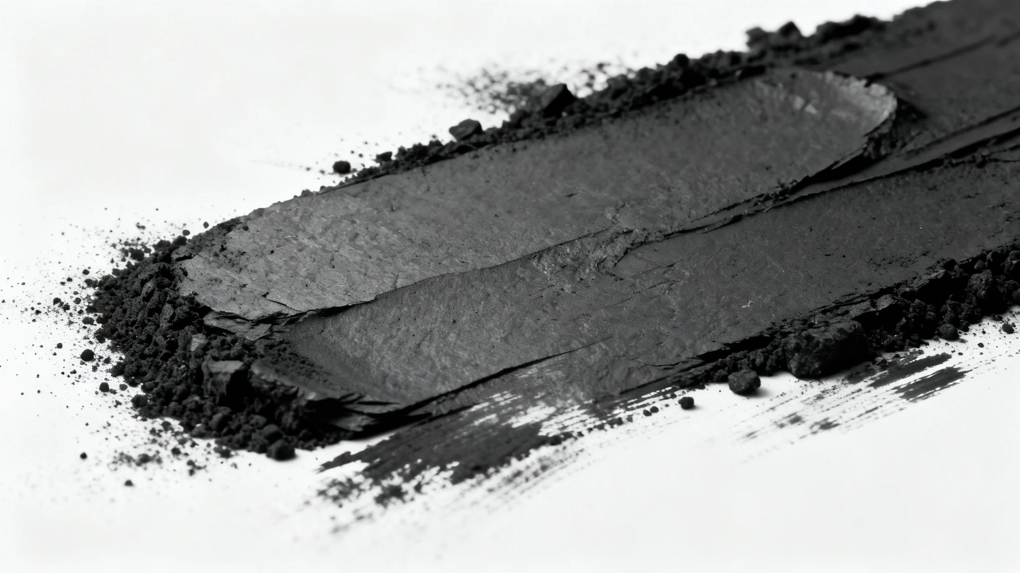 A close-up, detailed photograph of a dark charcoal texture, showcasing its rough, grainy surface against a stark white background.