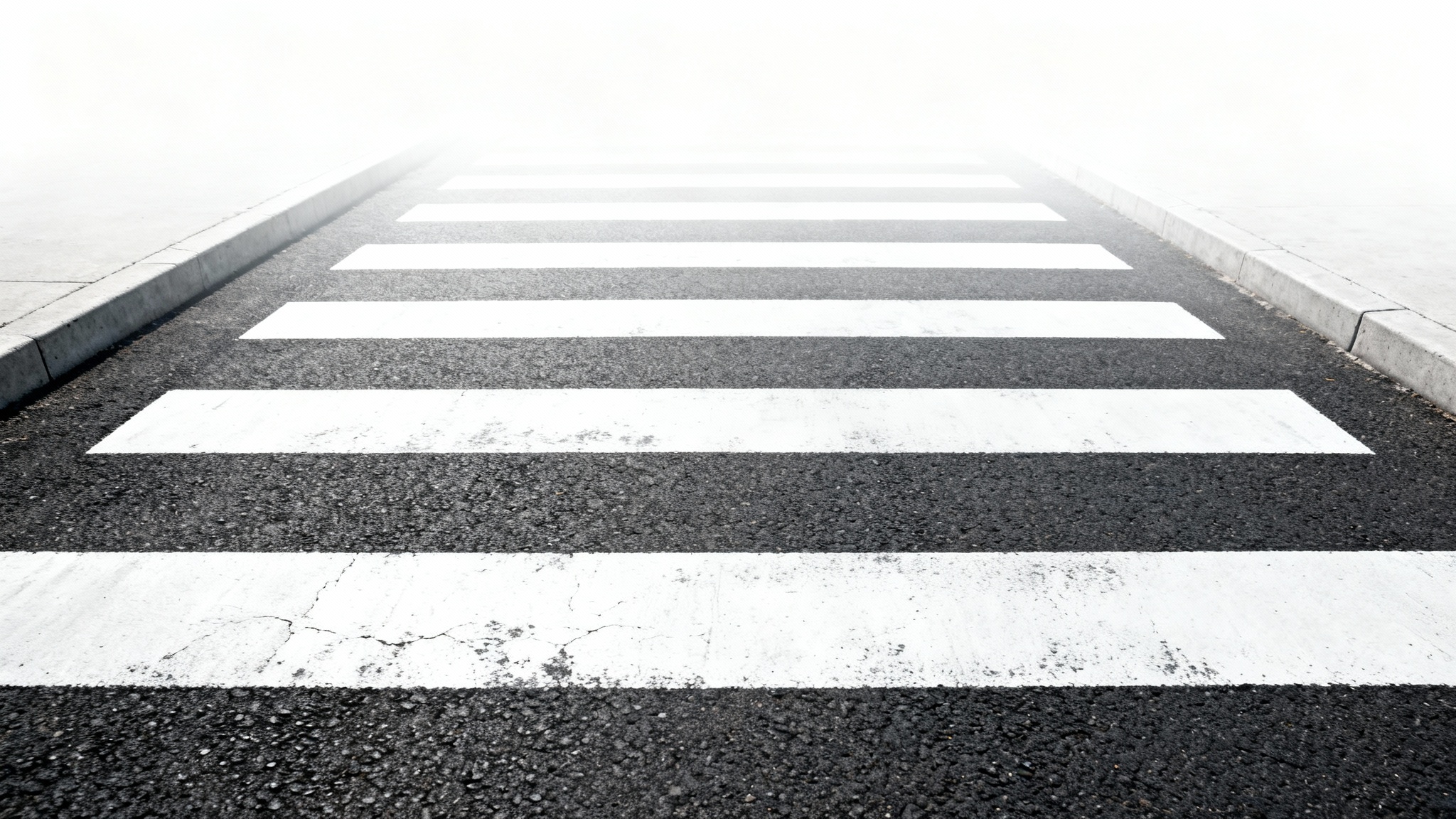 A minimalist, top-down photograph of a black asphalt crosswalk with bold white stripes, set against a clean white background.