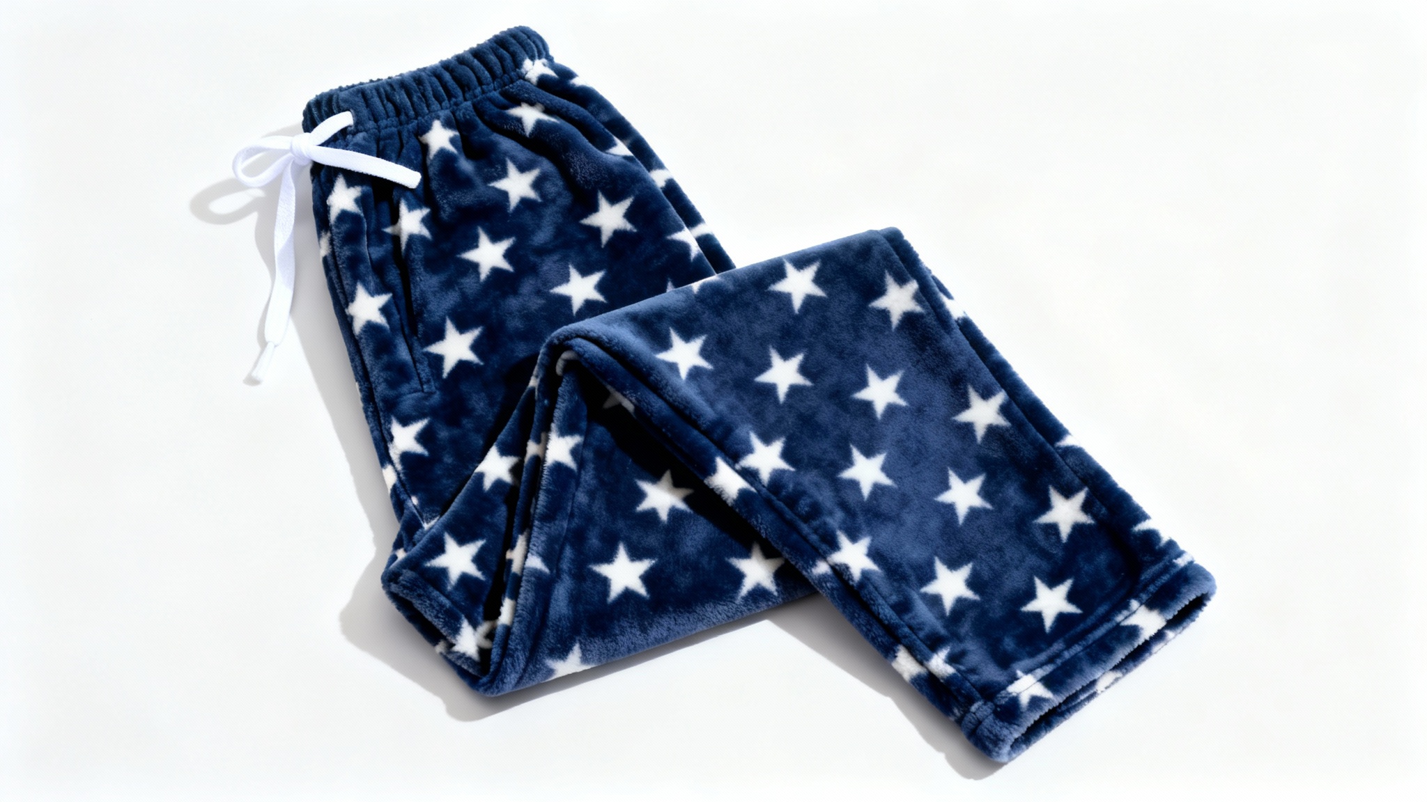 A photorealistic mockup of a pair of navy blue pajama pants with a white star pattern, displayed in a flat-lay style against a clean white background.