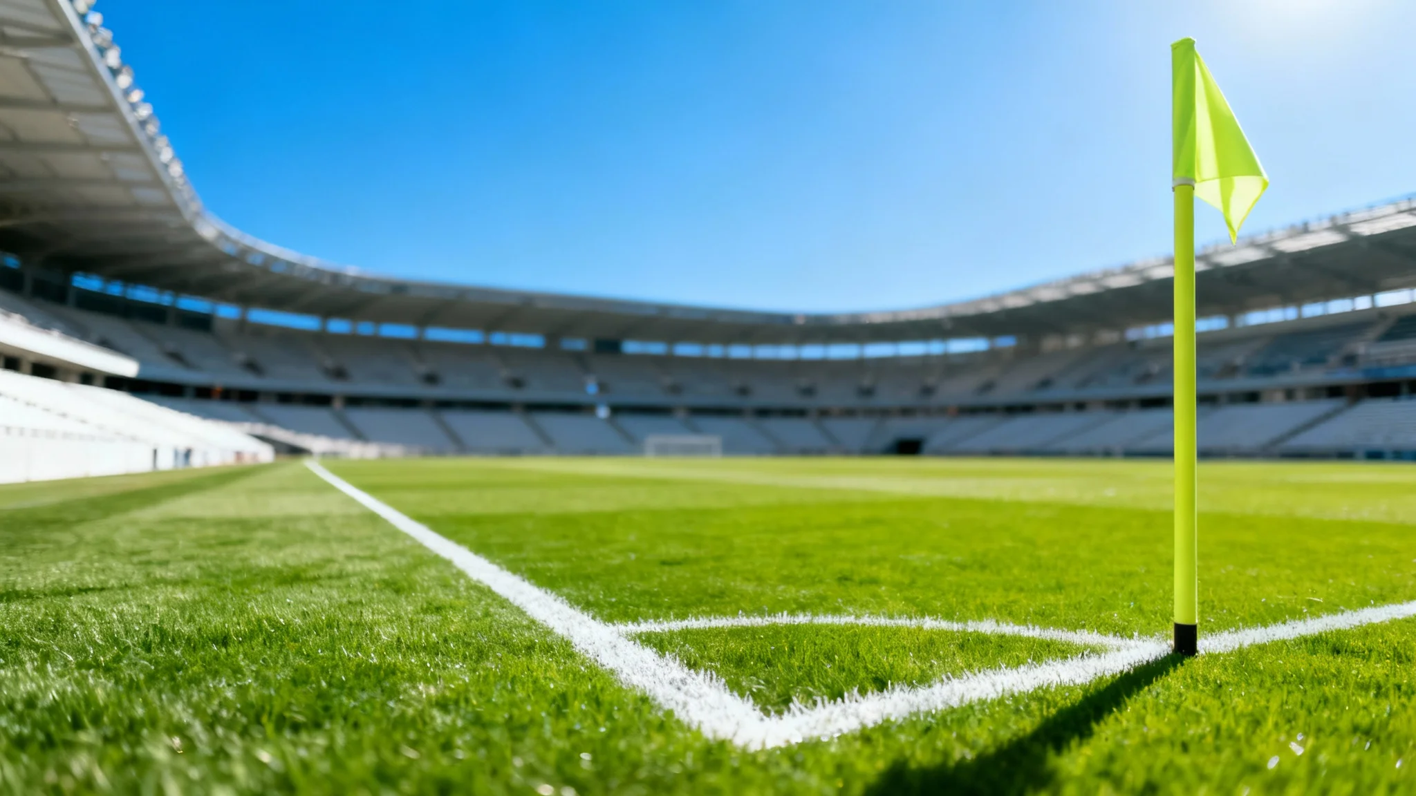 A stunning, wide-angle photograph of an empty professional soccer field on a sunny day, viewed from the corner flag, highlighting the perfect green grass and white lines.