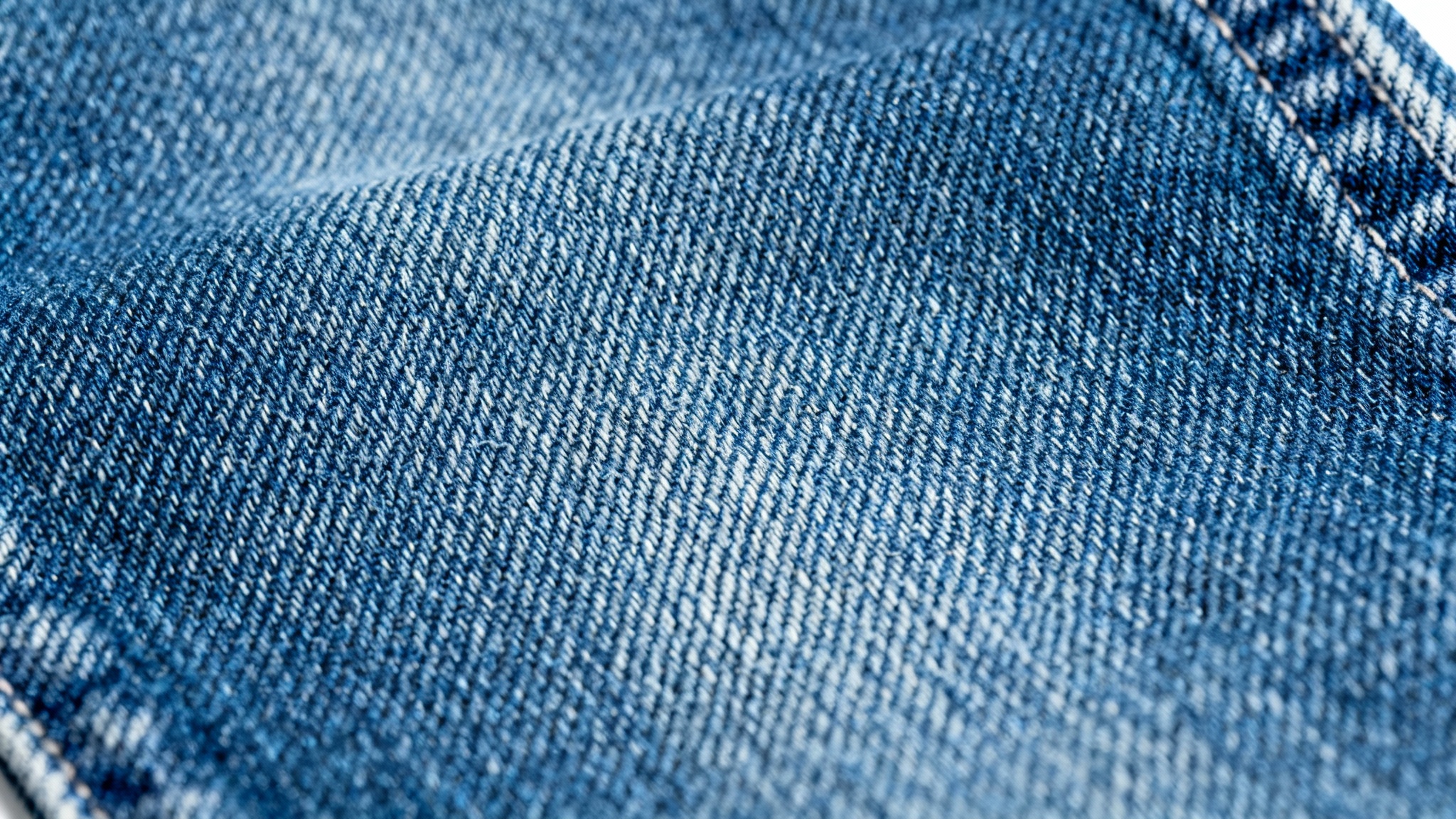 A detailed, close-up macro shot of a classic blue denim fabric, showing the intricate twill weave and texture of the material.