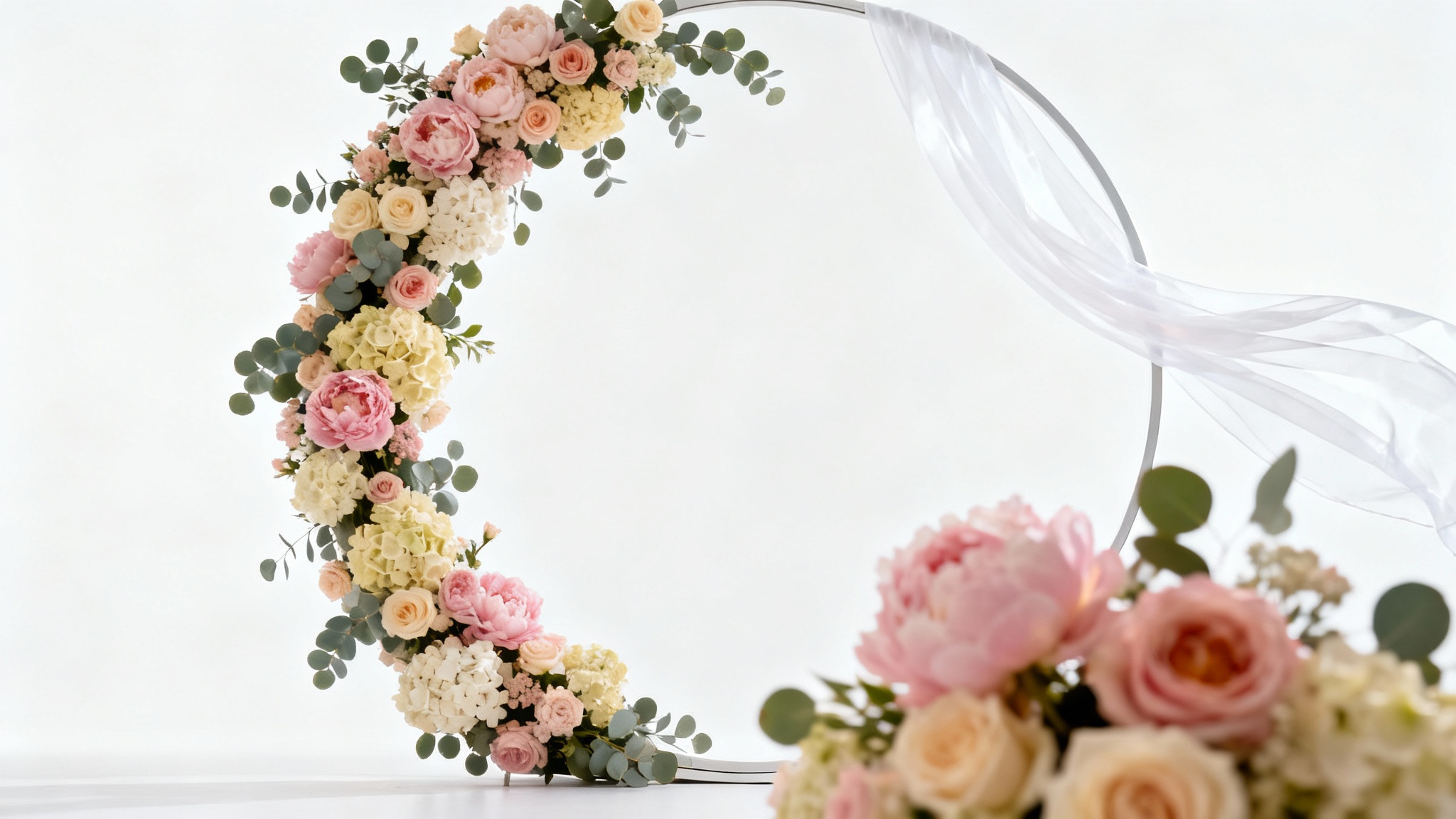 A photorealistic mockup of a circular wedding backdrop decorated with pink and white flowers and sheer white fabric, set against a white background.