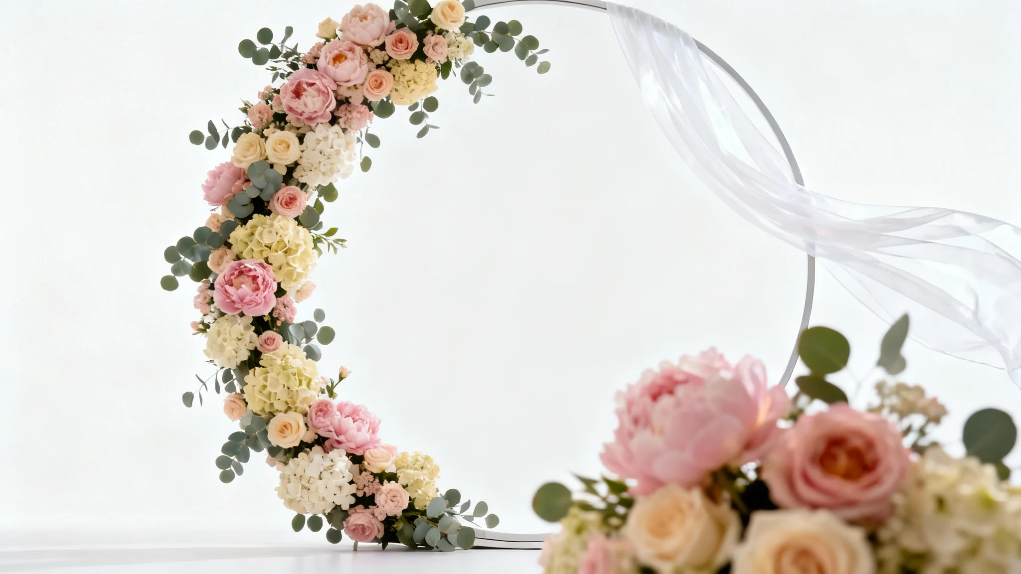 A photorealistic mockup of a circular wedding backdrop decorated with pink and white flowers and sheer white fabric, set against a white background.