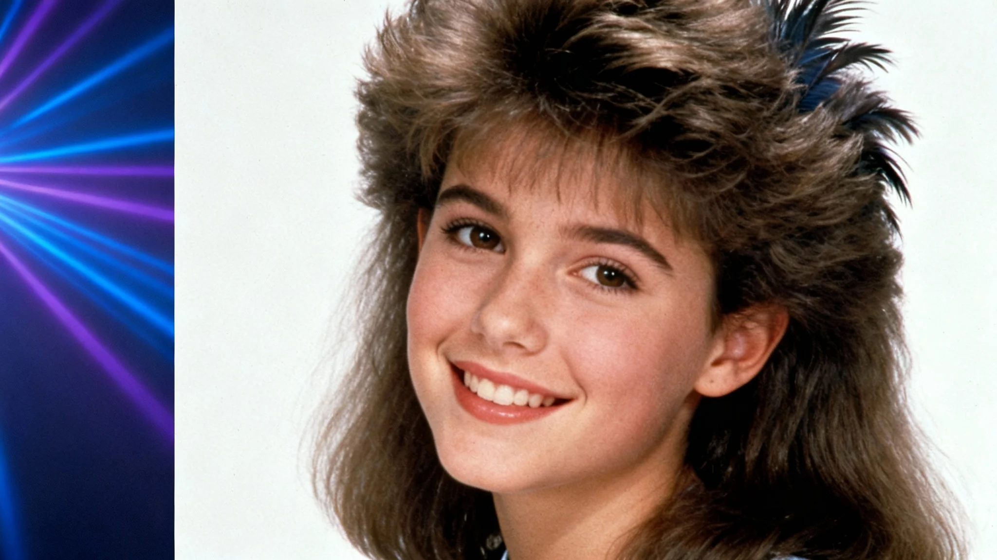 A classic 1990s yearbook portrait of a teenage girl with big, feathered hair, smiling in front of a blue and purple laser background.