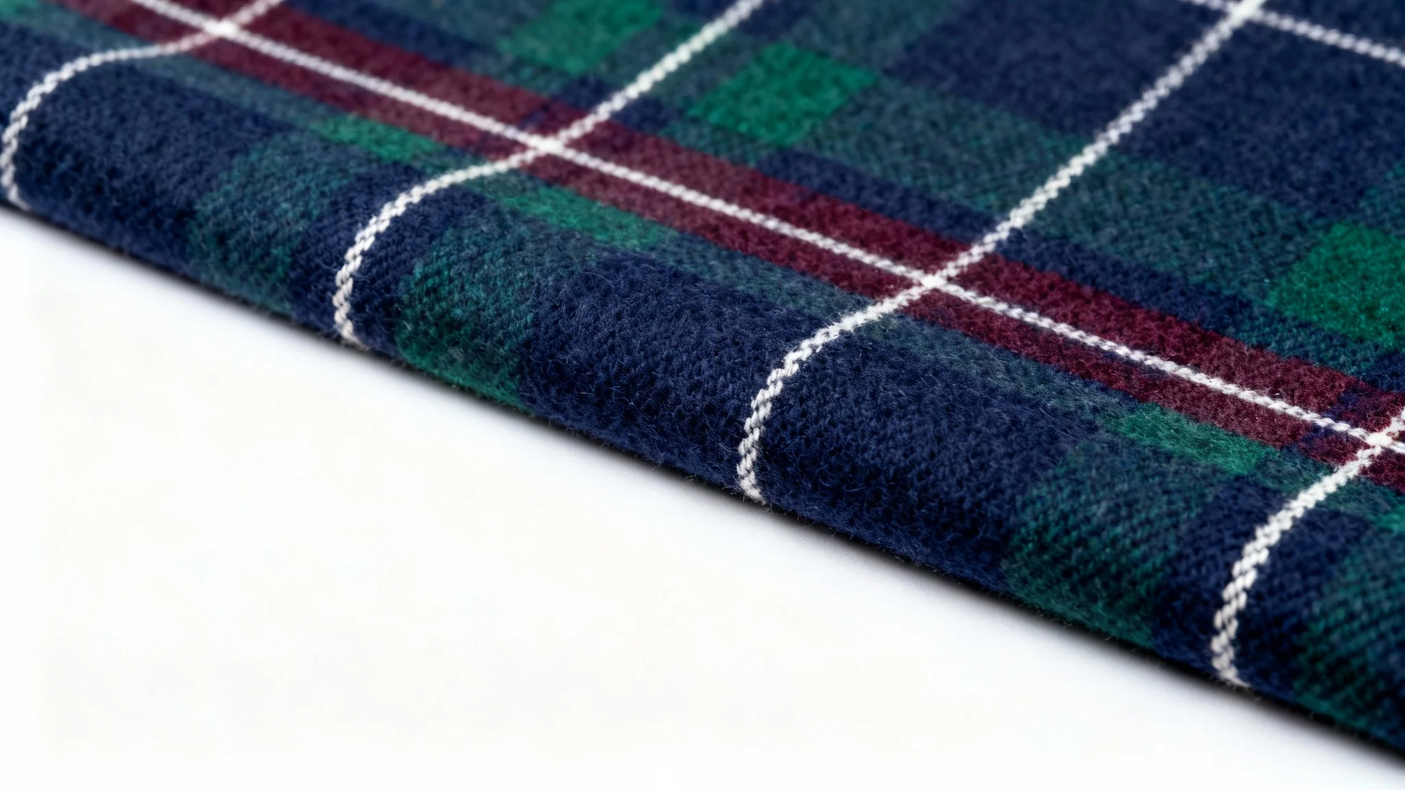 A close-up, detailed photograph of a fabric swatch with a sophisticated plaid pattern in navy, green, and burgundy against a stark white background.