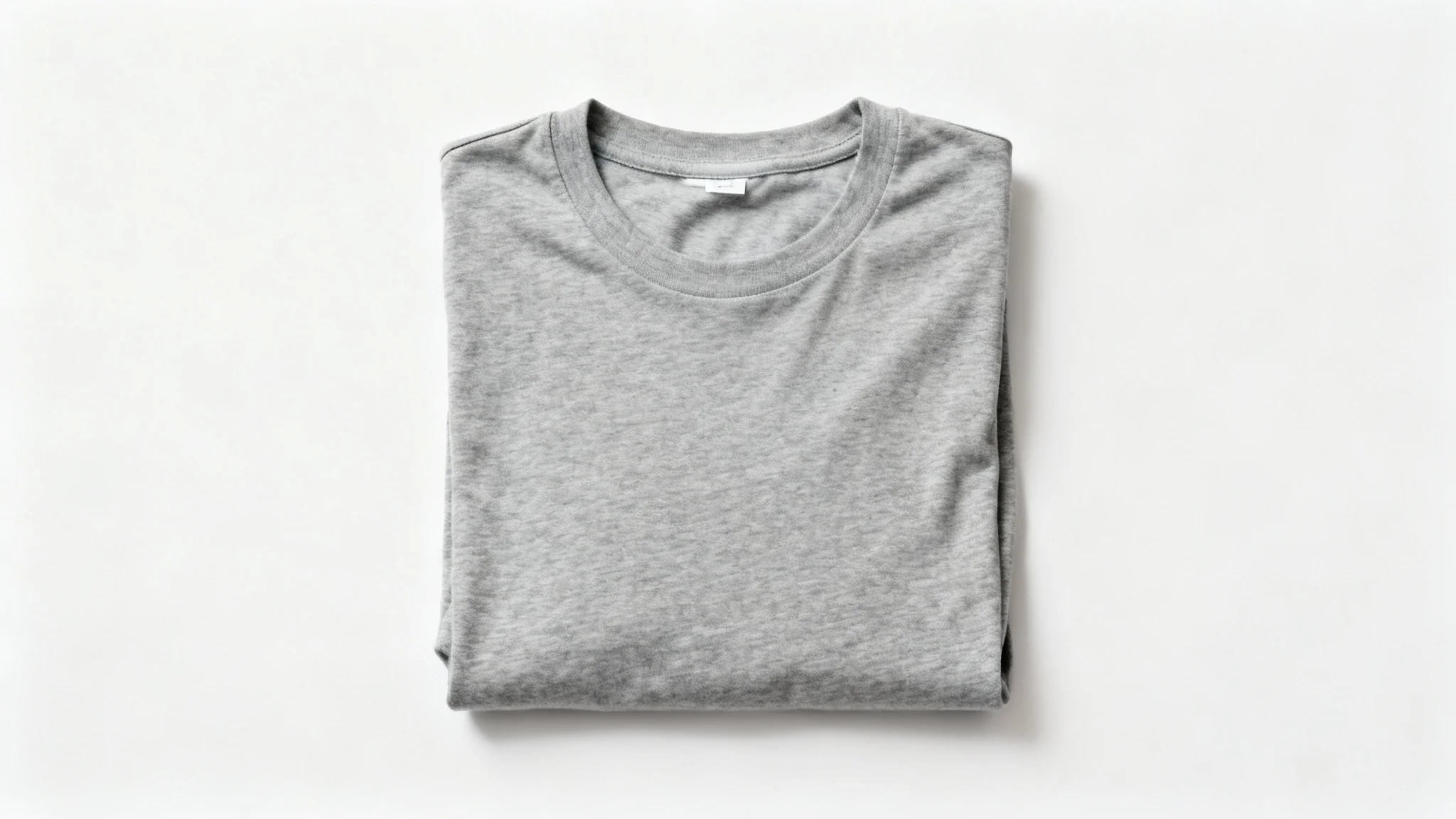 A photorealistic image of a neatly folded gray t-shirt with no logo, displayed on a clean white background, demonstrating the removal of a brand mark.