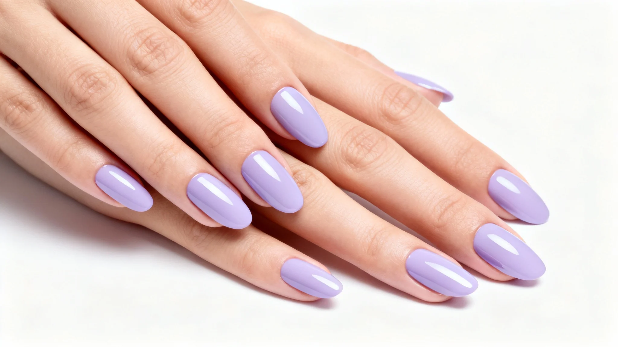 A close-up photograph of a woman's hands with perfect, glossy pastel lavender gel nails in an almond shape, set against a plain white background.